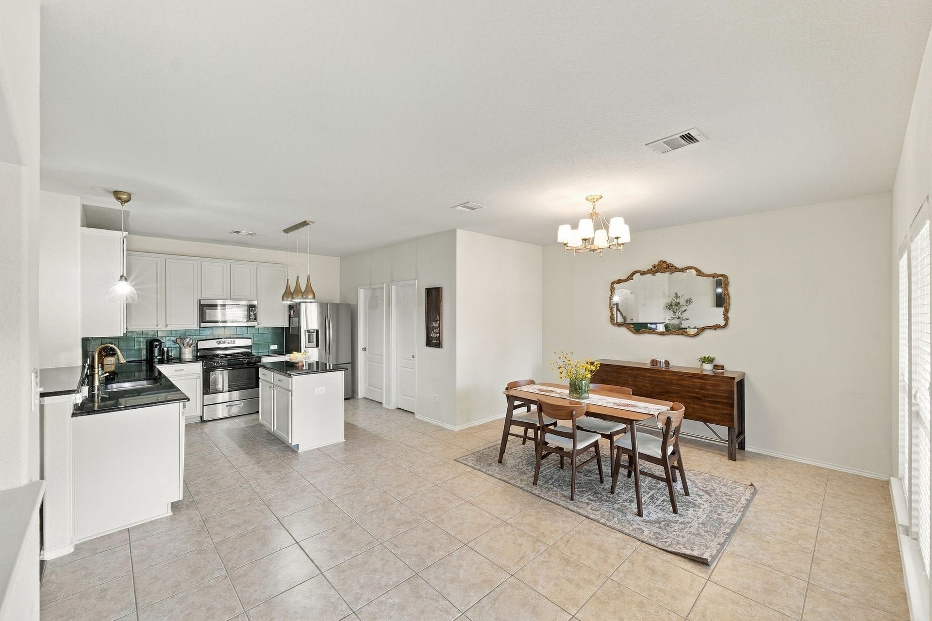 26037 Kings Mill Crest Drive, Kingwood, TX 77339 Spacious open-concept kitchen and dining area with modern stainless steel appliances, sleek white cabinetry, and elegant tile flooring, perfect for entertaining.