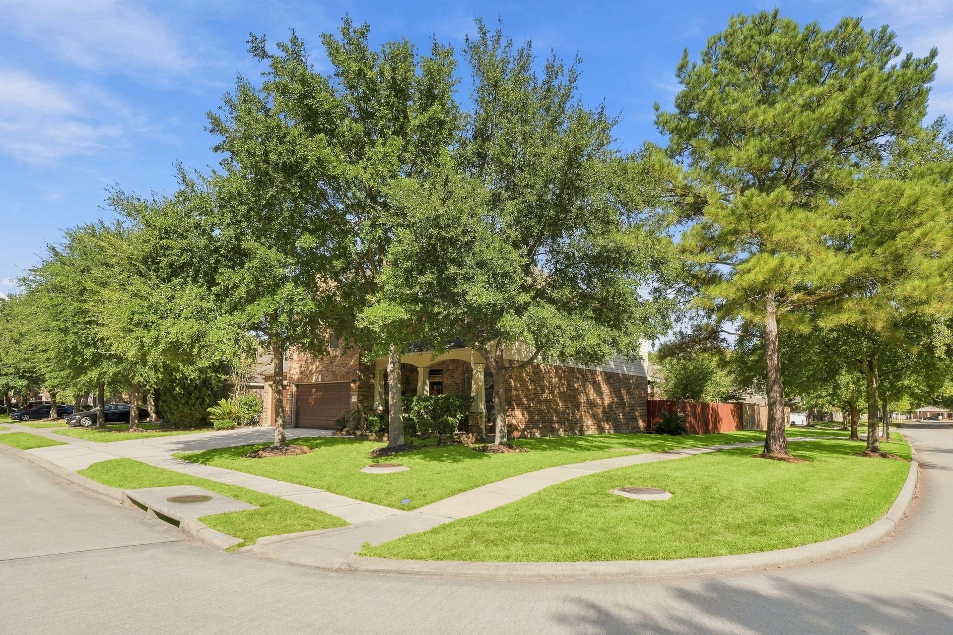 26037 Kings Mill Crest Drive, Kingwood, TX 77339 Charming corner lot home with lush landscaping and mature trees, offering great curb appeal and a welcoming entrance.