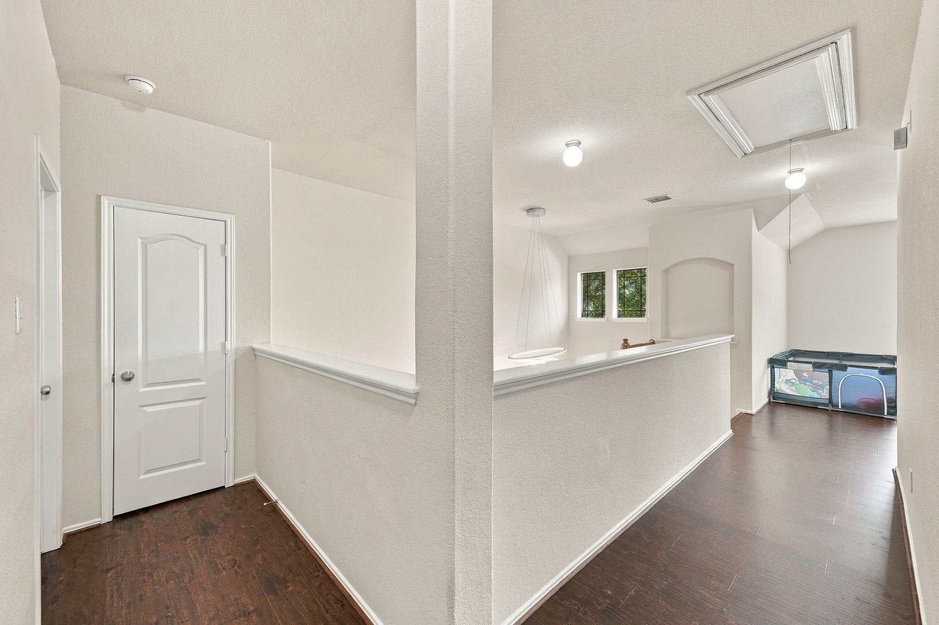 26037 Kings Mill Crest Drive, Kingwood, TX 77339 Bright upstairs hallway with dark wood flooring leads to a versatile open space perfect for a play area or lounge, featuring a storage closet and access to additional rooms.