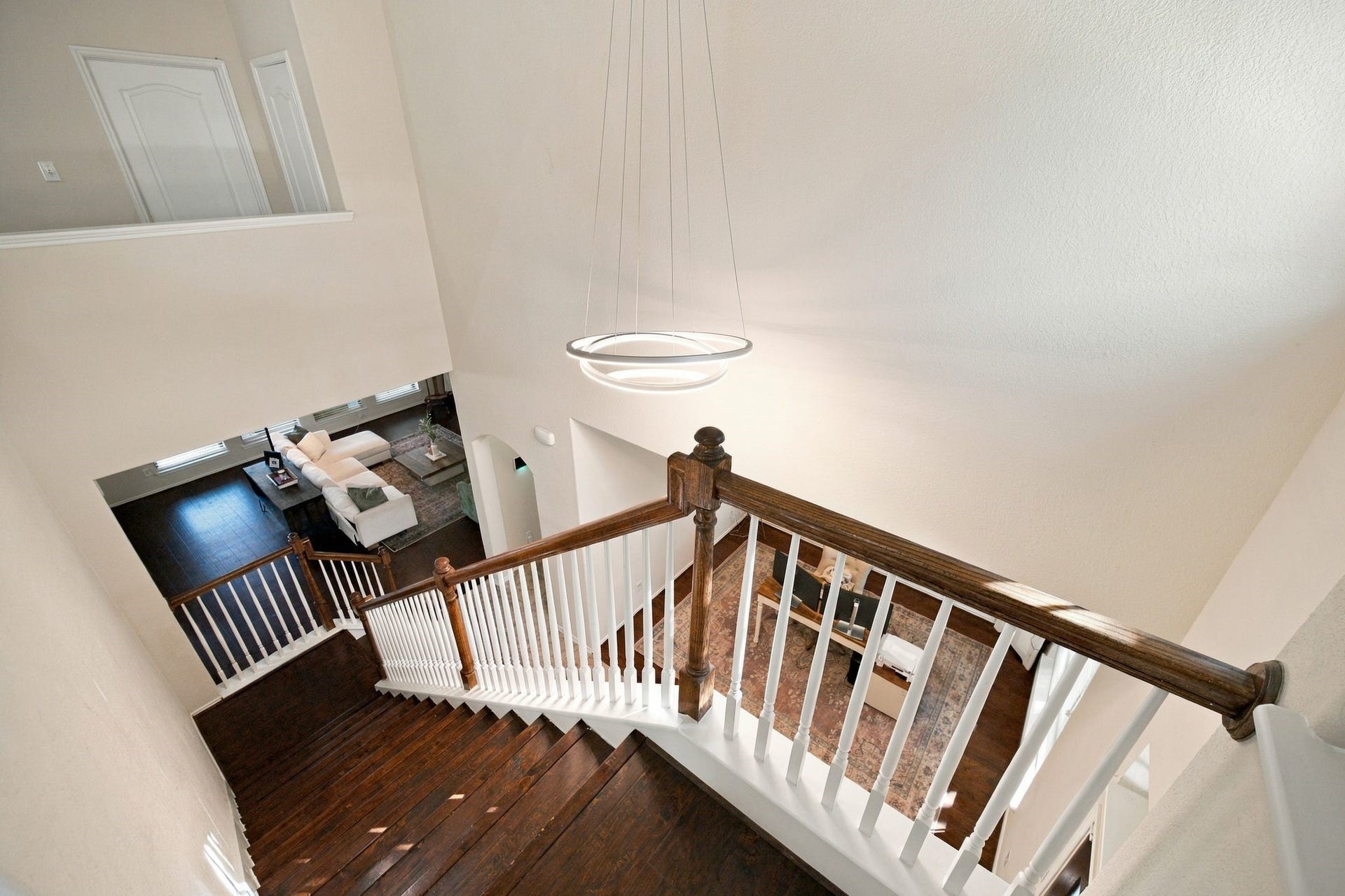 26037 Kings Mill Crest Drive, Kingwood, TX 77339 Elegant staircase with dark wood treads and white balusters leads to a bright, open living area featuring modern lighting and high ceilings.