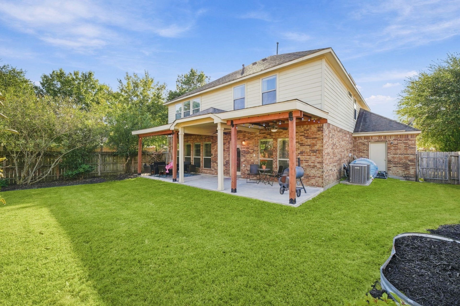 26037 Kings Mill Crest Drive, Kingwood, TX 77339 Charming two-story home with a spacious backyard, featuring a covered patio perfect for outdoor entertaining, surrounded by lush greenery for added privacy.