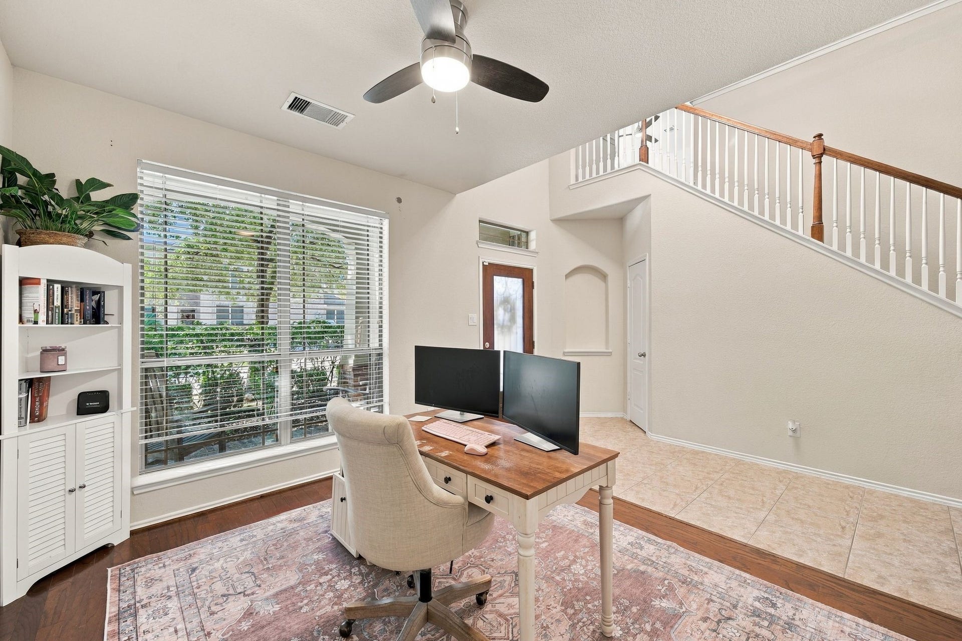 26037 Kings Mill Crest Drive, Kingwood, TX 77339 Bright and inviting home office with large windows, elegant flooring, and a stylish staircase, perfect for productivity and comfort.