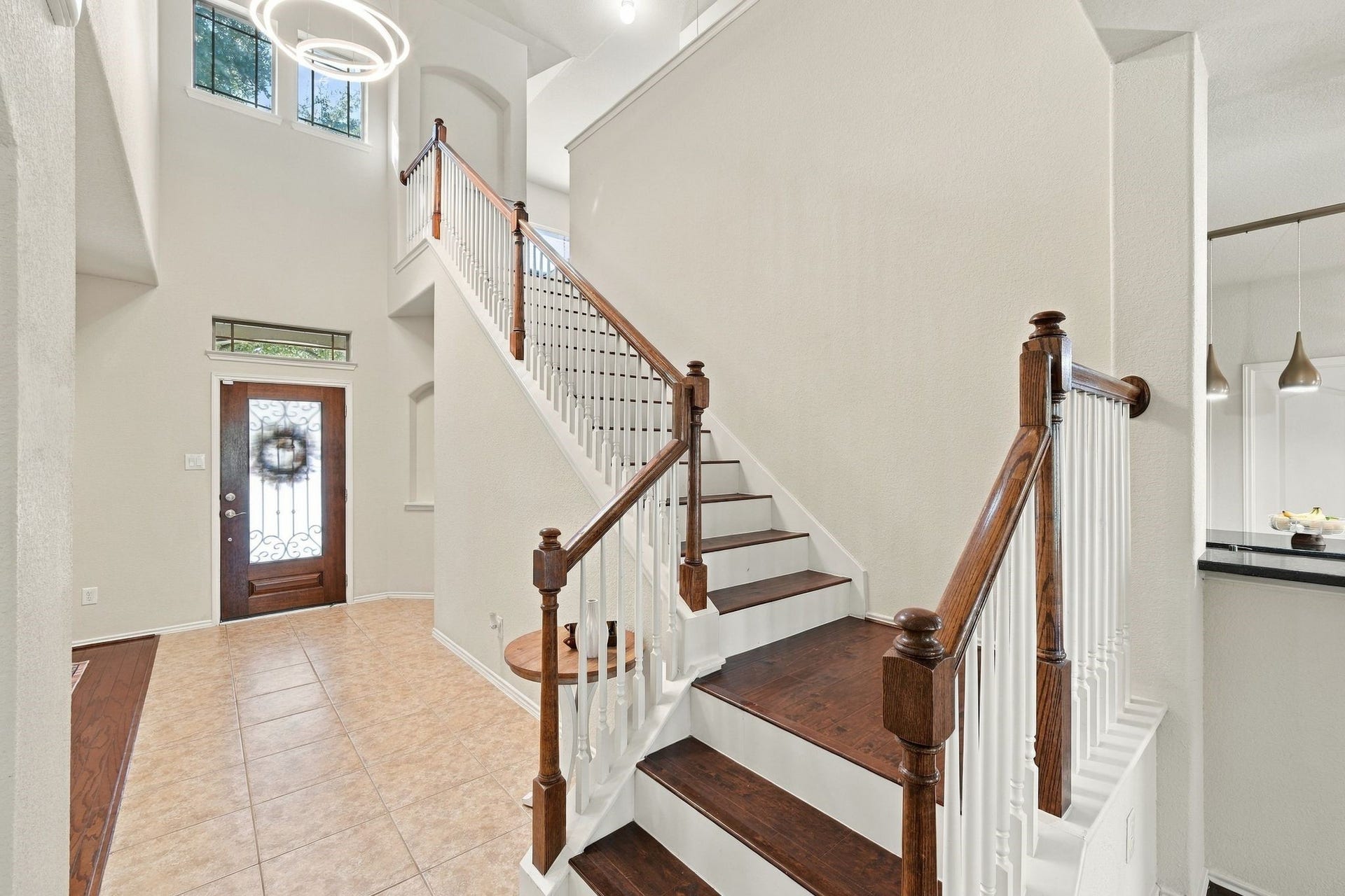 26037 Kings Mill Crest Drive, Kingwood, TX 77339 Elegant entryway with high ceilings, featuring a beautiful wooden staircase with white balusters and a stylish modern chandelier, creating a welcoming ambiance.