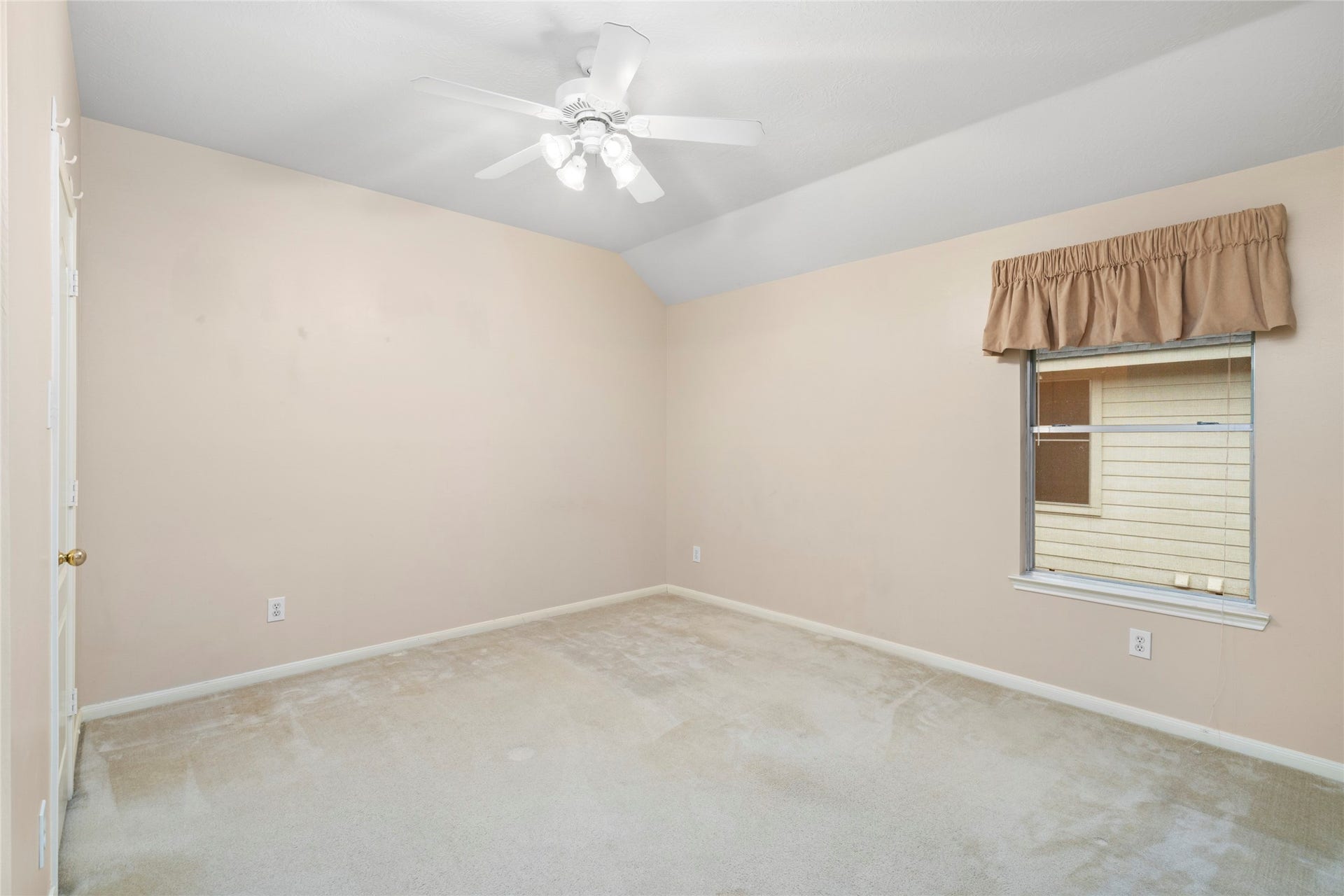 Bright secondary bedroom with neutral walls, ceiling fan, and large window bringing in natural light. The clean palette gives buyers a flexible starting point for a child's room, guest bedroom, home office, or personal retreat.