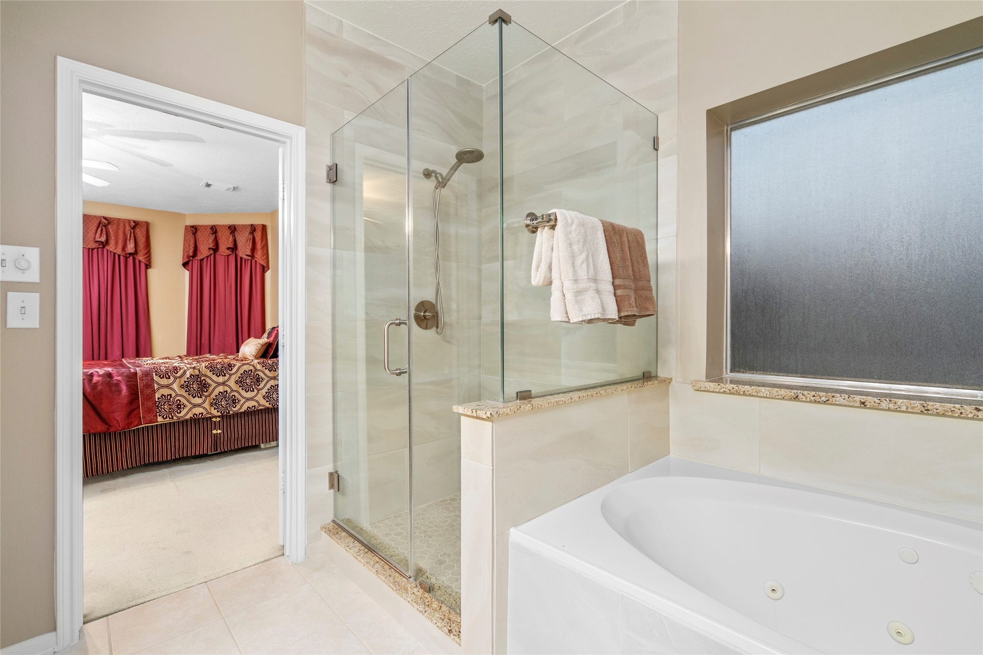 Primary bathroom designed as a private retreat, featuring a large glass-enclosed shower and a relaxing soaking/jetted tub. The generous layout gives buyers the opportunity to create a spa-inspired space for unwinding at the end of the day.