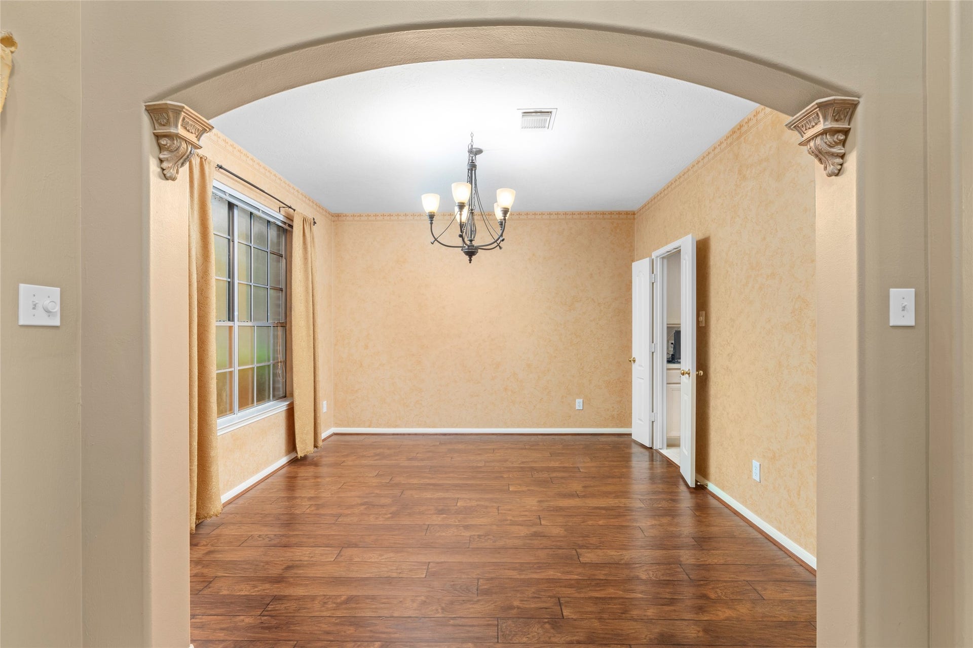 Elegant formal dining room positioned to make entertaining feel effortless, with an arched opening and large window bringing in natural light. The generous proportions and architectural character offer a dedicated dining space while maintaining an easy connection to the rest of the home.