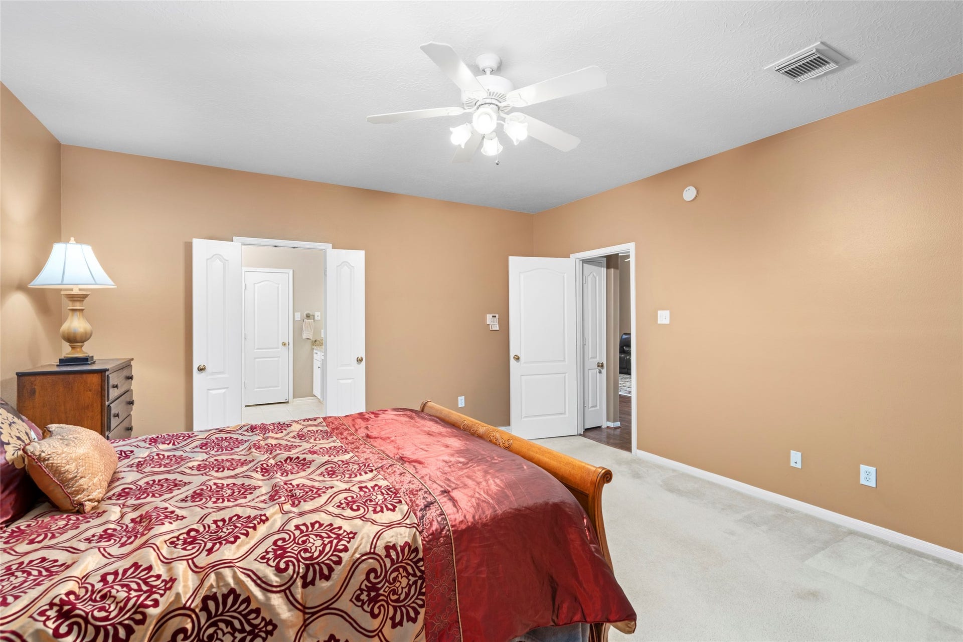 Comfortable bedroom with natural light, a ceiling fan, and a warm neutral setting that can easily adapt to different lifestyles. The room's proportions and double-door access offer flexibility for a bedroom, guest retreat, or personal space.