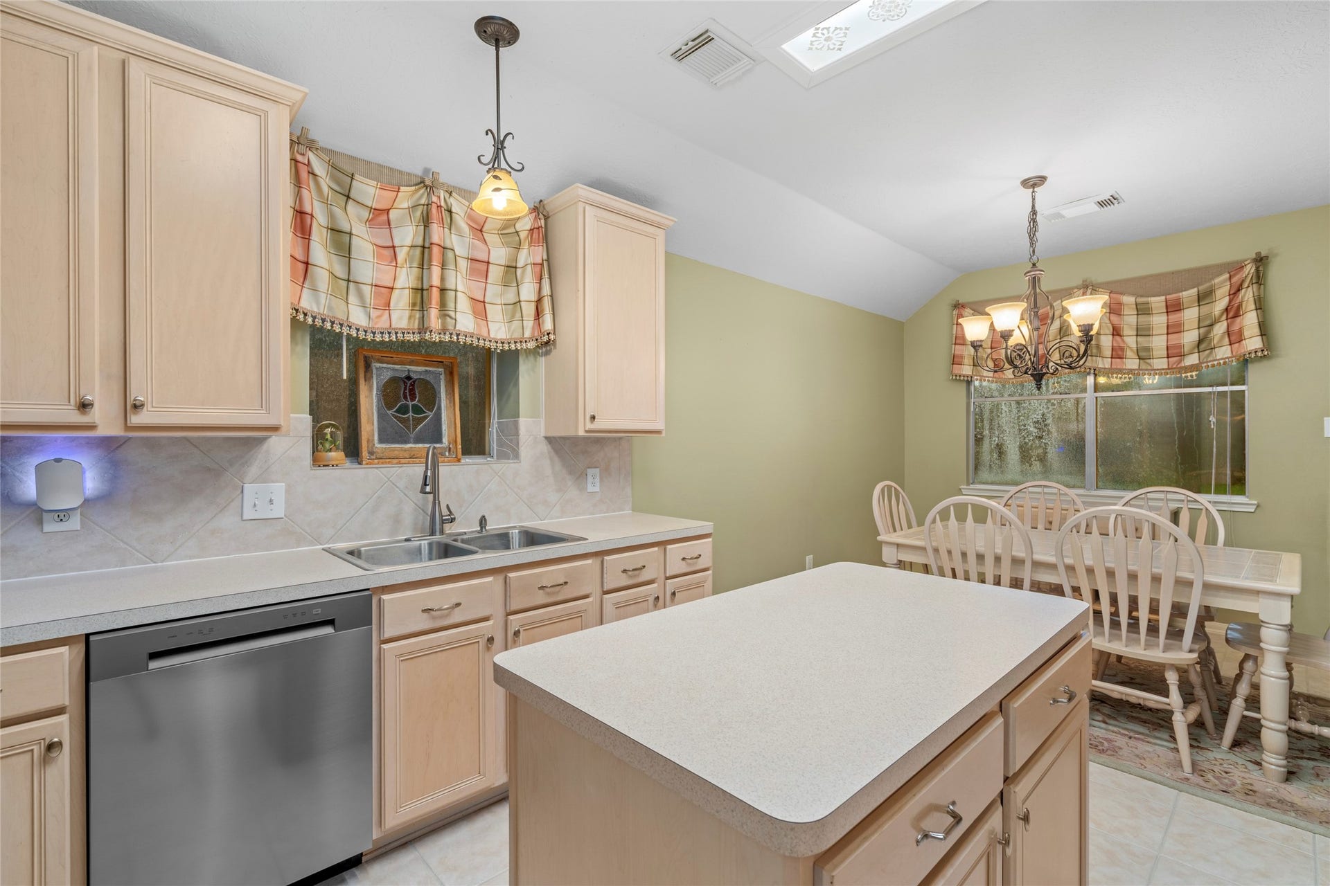 Another view highlights the kitchen's central island, generous cabinetry, and adjoining breakfast area. The combination of workspace and casual dining creates a practical hub for daily routines and entertaining.