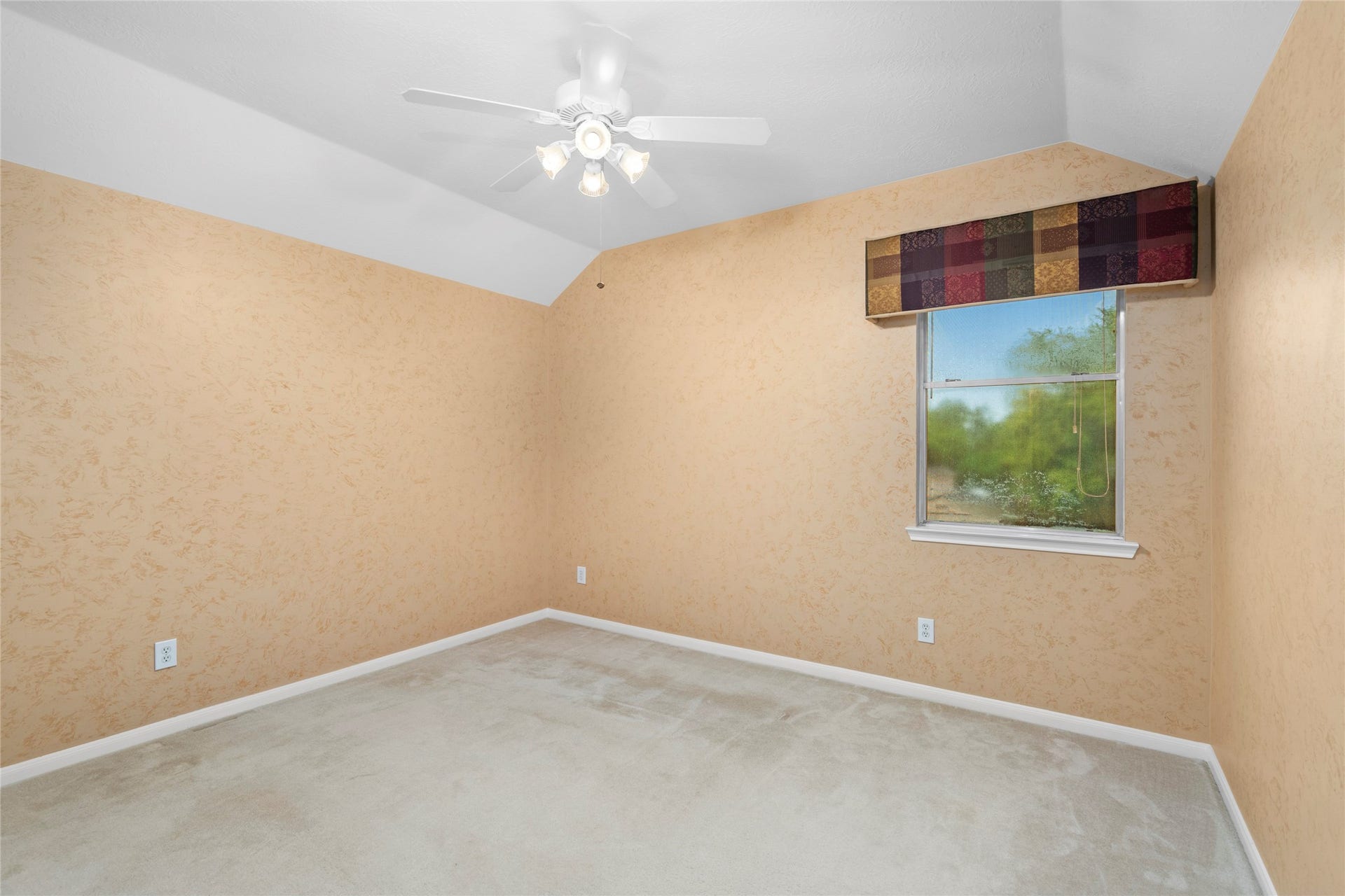 Comfortable bedroom with textured walls, ceiling fan, and a window overlooking the outdoors. The peaceful setting and flexible layout make this a natural option for a bedroom, guest space, or home office.