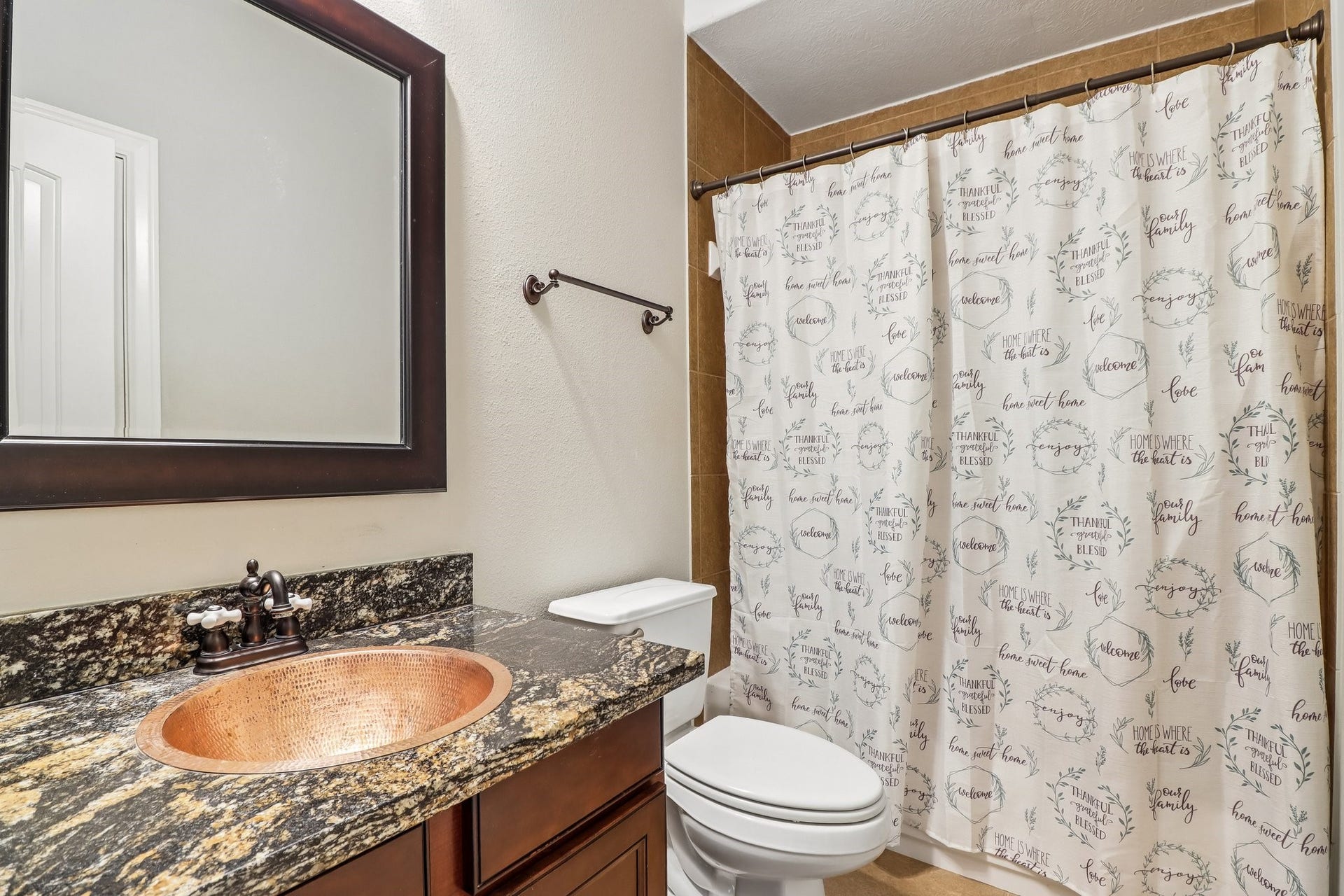 22715 Wilbur Lane, Tomball, TX 77375 Charming bathroom featuring a granite countertop with a copper sink, complemented by a stylish shower curtain and warm wood cabinetry.