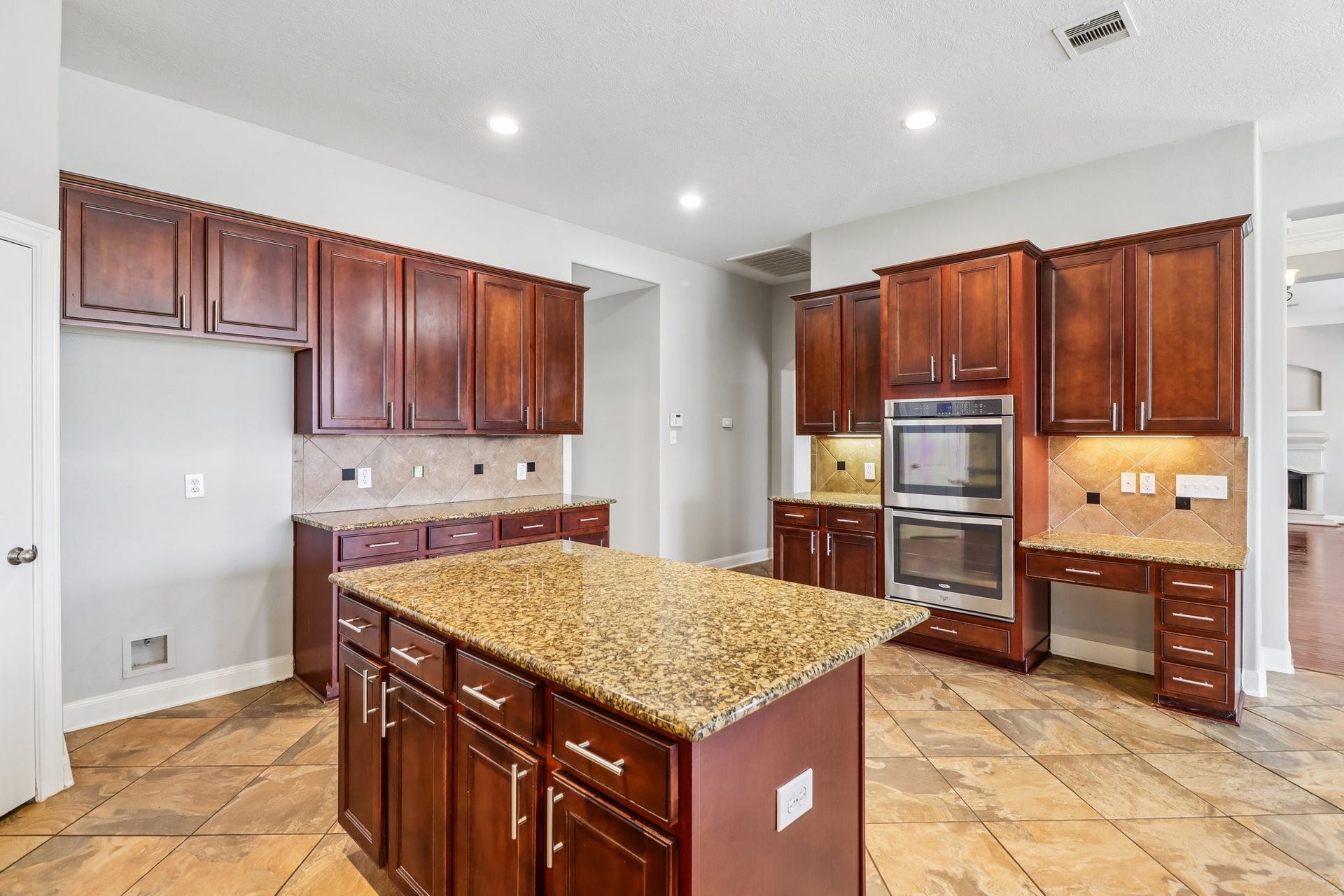 22715 Wilbur Lane, Tomball, TX 77375 Spacious kitchen with rich wooden cabinetry, granite countertops, double ovens, and a central island, perfect for culinary enthusiasts.