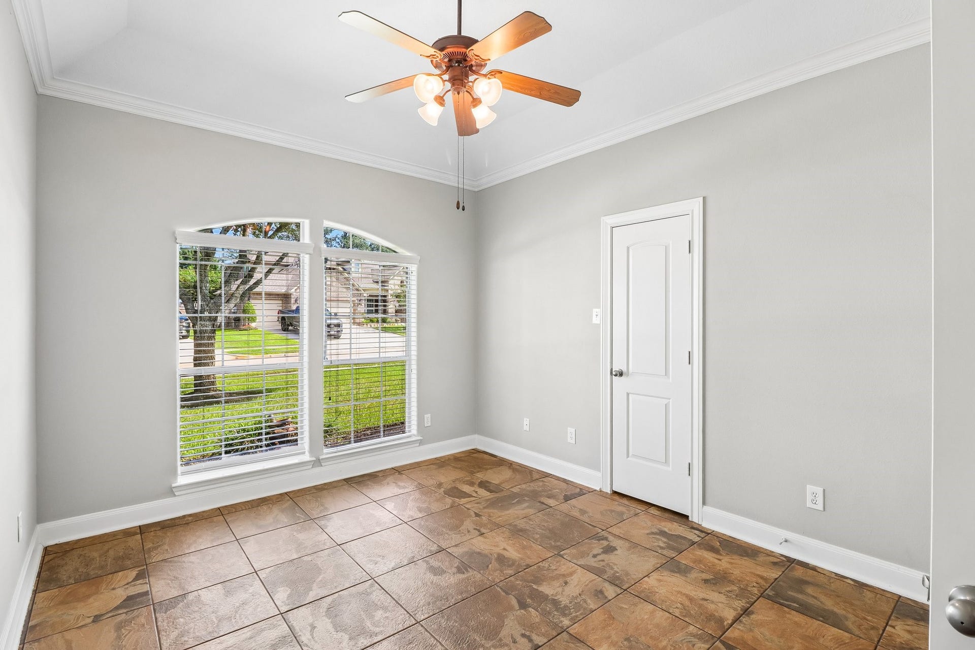 22715 Wilbur Lane, Tomball, TX 77375 Bright room with a large arched window, neutral walls, and tiled flooring, enhanced by a ceiling fan for comfort.