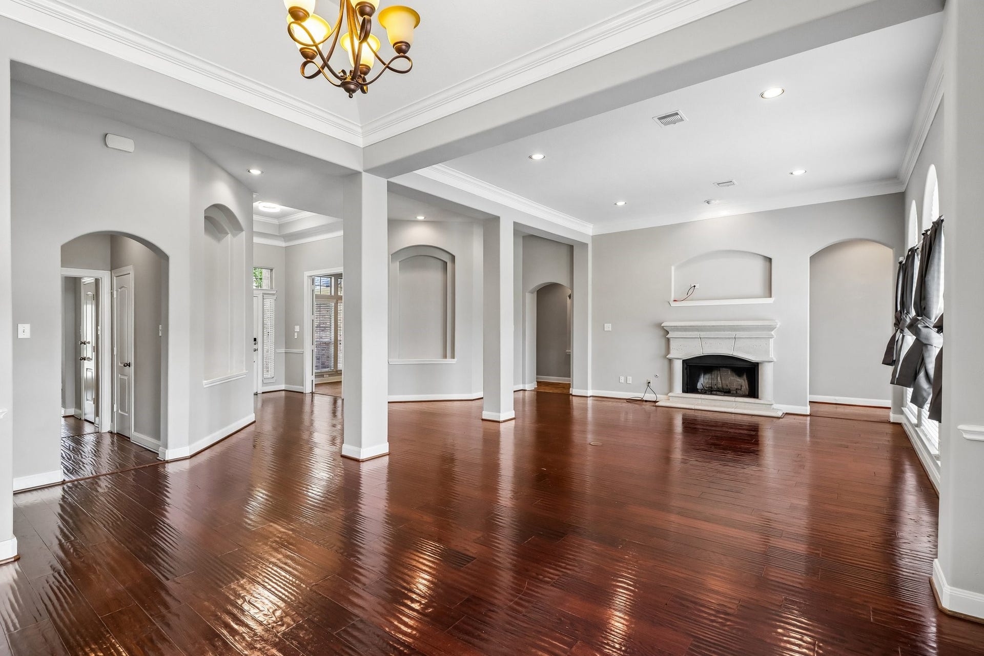 22715 Wilbur Lane, Tomball, TX 77375 Spacious living area with elegant hardwood floors, a cozy fireplace, and abundant natural light from large windows, framed by graceful arches and recessed lighting.