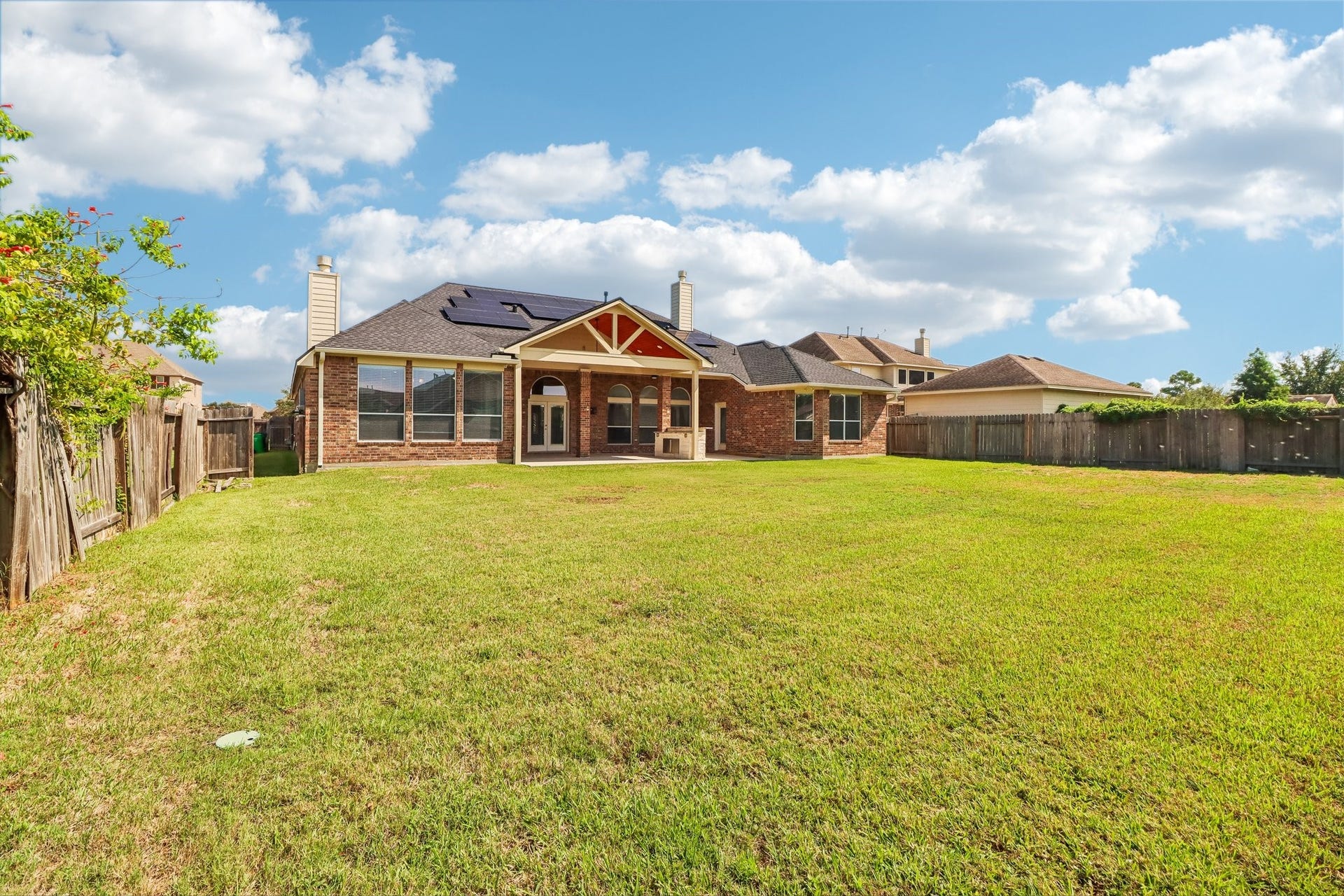 22715 Wilbur Lane, Tomball, TX 77375 Spacious backyard with a well-maintained lawn and a charming brick exterior, perfect for outdoor gatherings and relaxation..