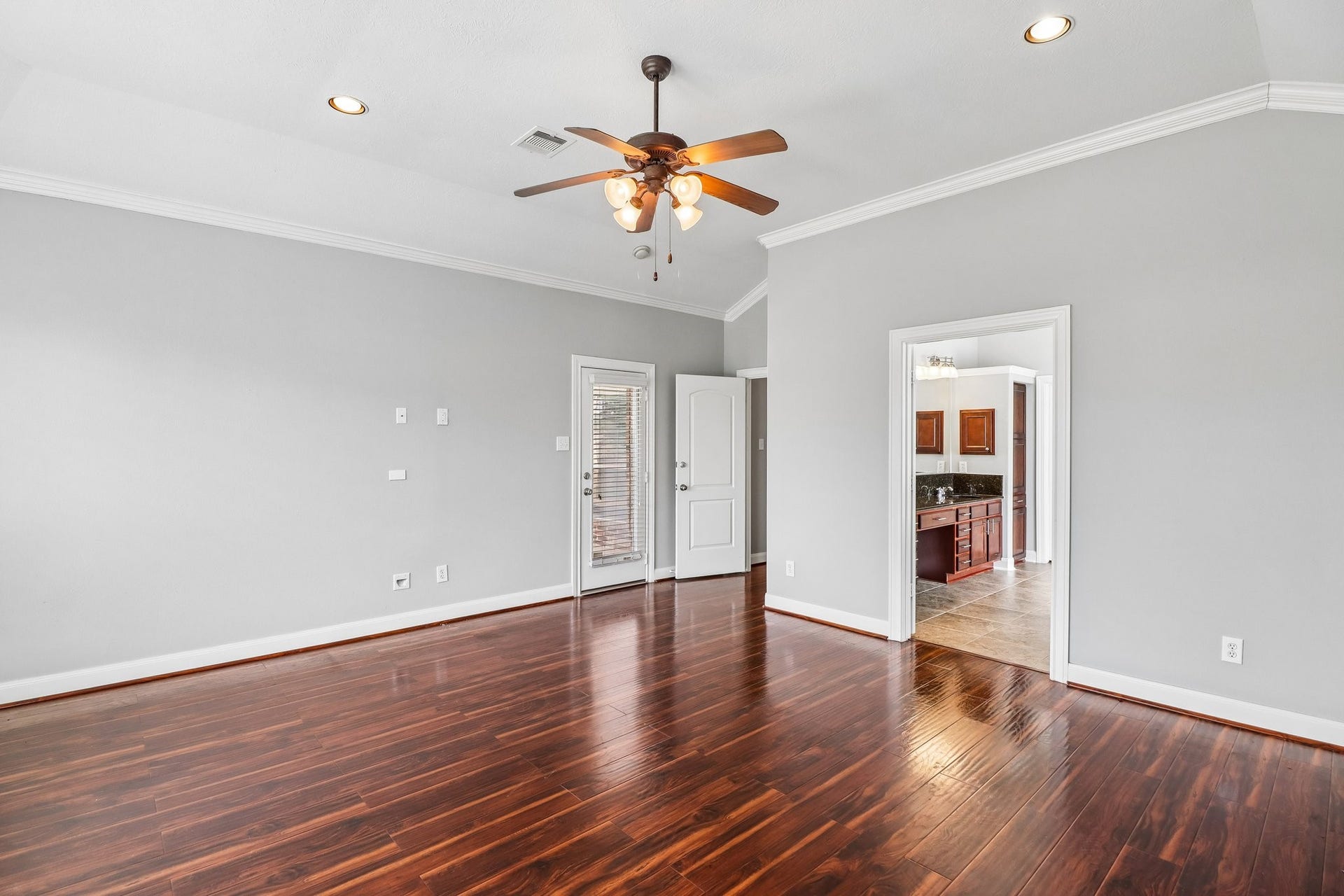 22715 Wilbur Lane, Tomball, TX 77375 Spacious room with rich hardwood floors, abundant natural light from large windows, and a ceiling fan, perfect for relaxation or entertaining.
