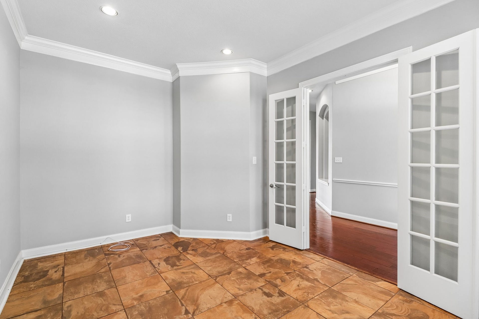 22715 Wilbur Lane, Tomball, TX 77375 Bright and inviting office featuring elegant French doors, crown molding, and warm tile flooring, perfect for a home office or cozy sitting area.