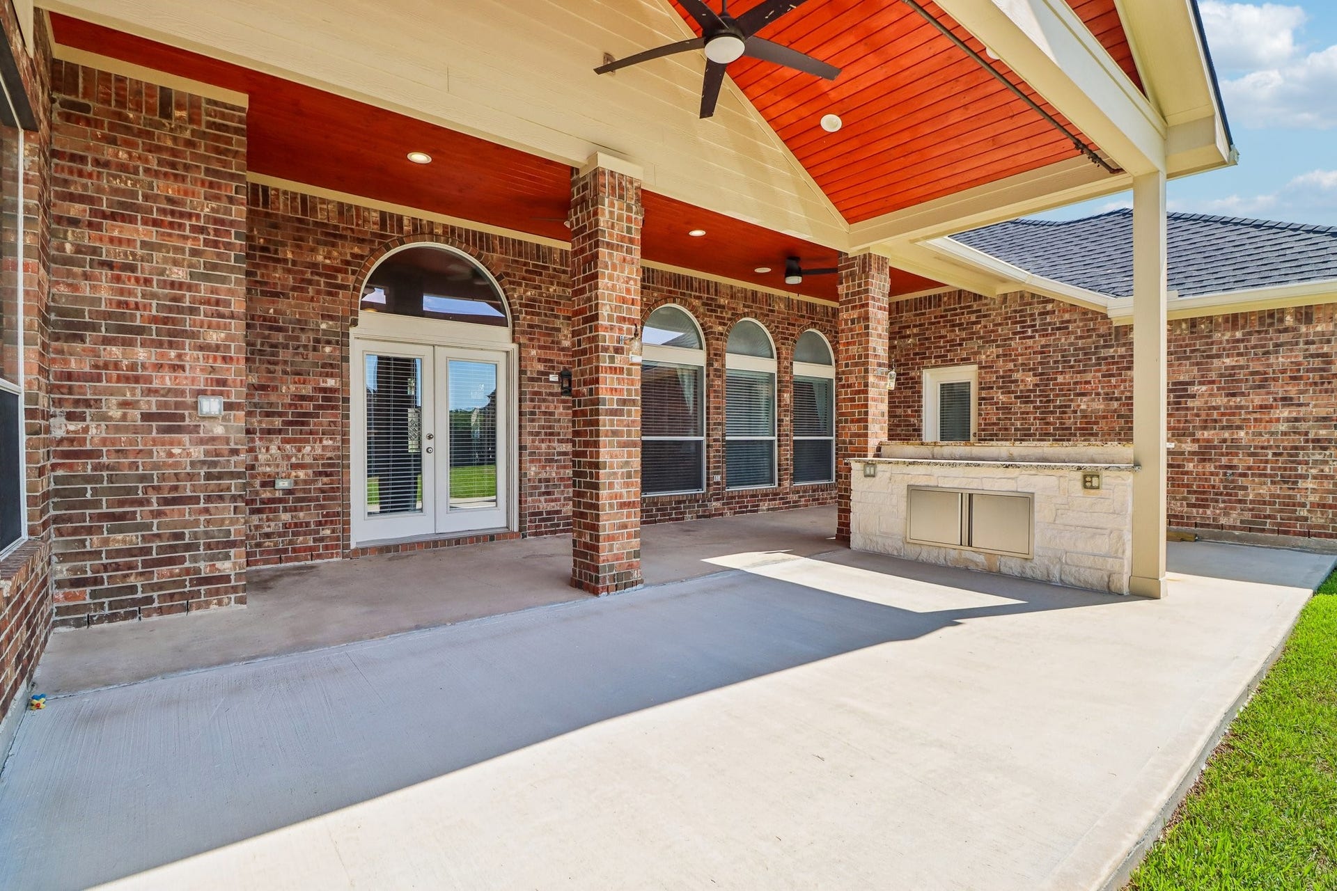 22715 Wilbur Lane, Tomball, TX 77375 Spacious covered patio with brick columns and a built-in outdoor kitchen overlooks a large, fenced backyard, perfect for entertaining and relaxation.
