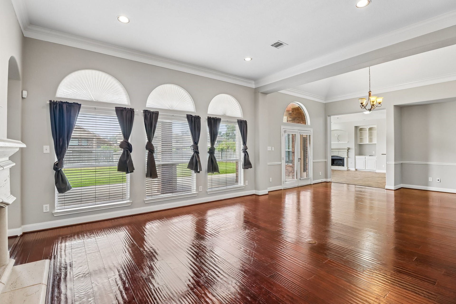 22715 Wilbur Lane, Tomball, TX 77375 Spacious living area with gleaming hardwood floors, abundant natural light from large arched windows, and elegant crown molding.