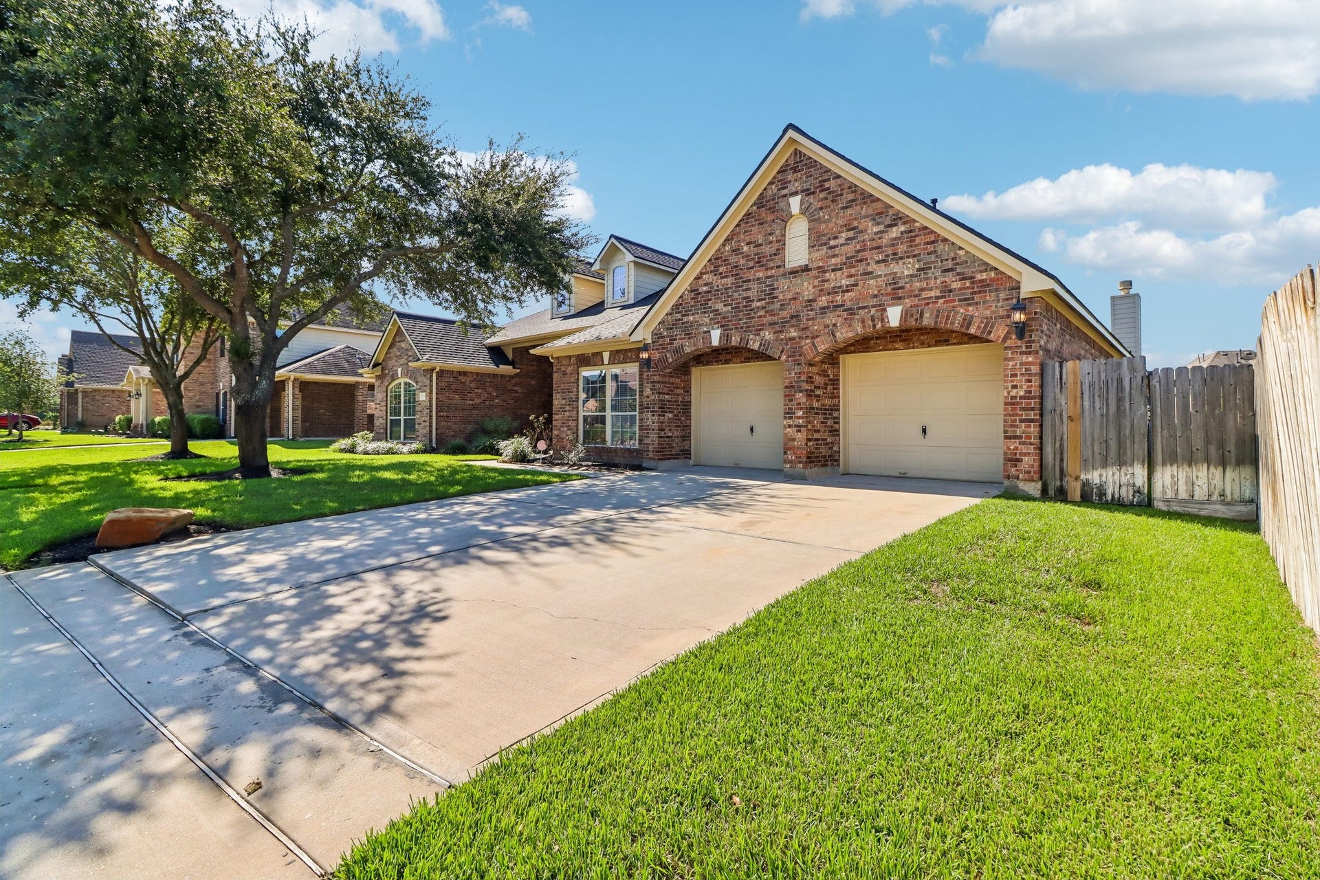 22715 Wilbur Lane, Tomball, TX 77375 Charming brick home with a spacious two-car garage and a well-maintained lawn, nestled in a serene neighborhood with mature trees.