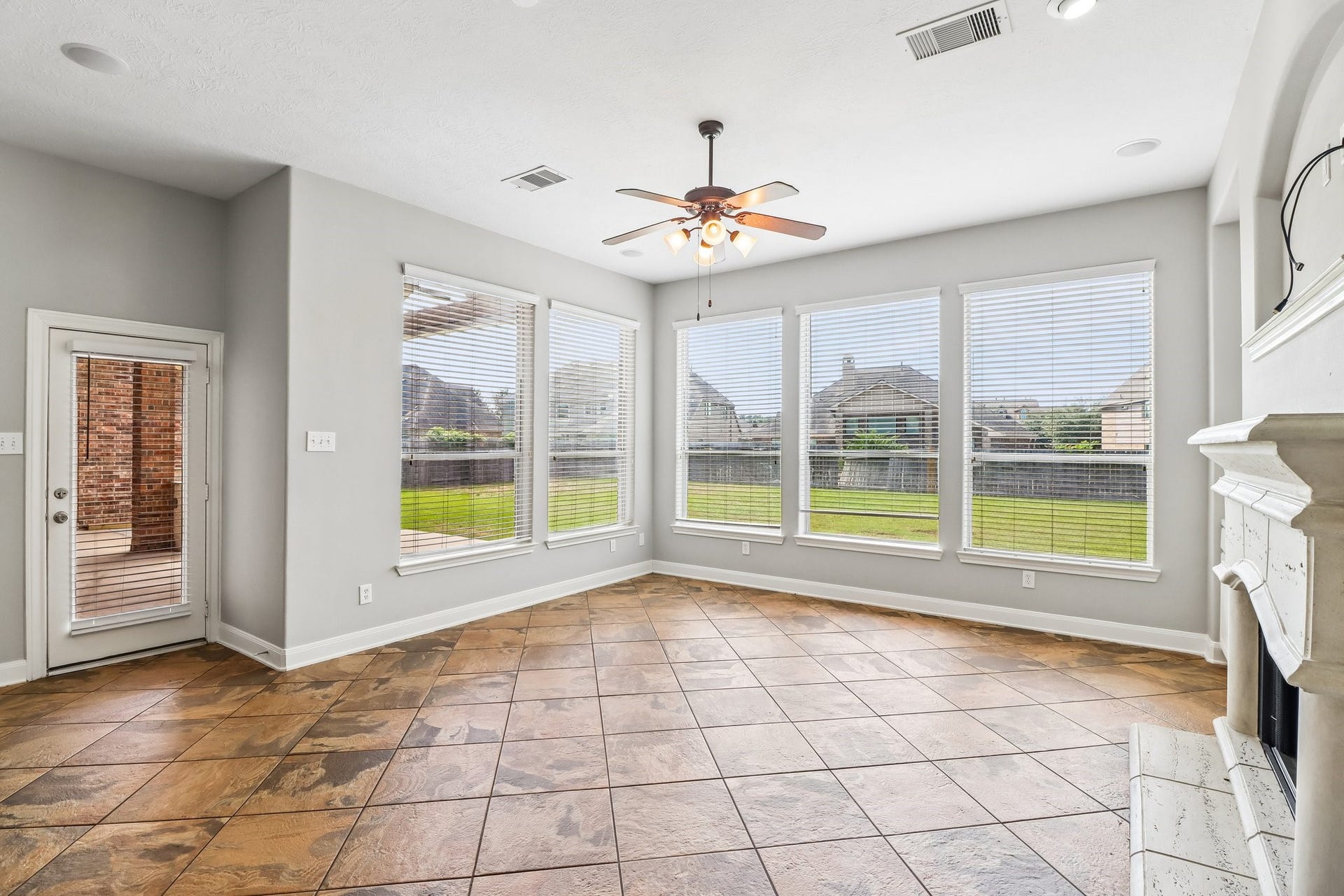 22715 Wilbur Lane, Tomball, TX 77375 Bright living area with large windows offering abundant natural light, a cozy fireplace, and elegant tile flooring, seamlessly connecting to the outdoor patio.