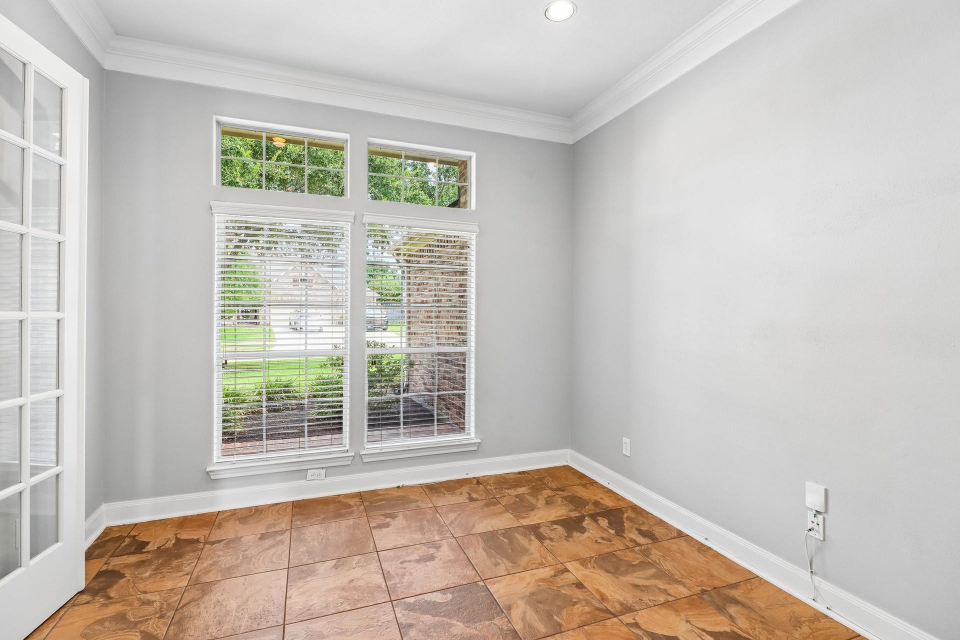 22715 Wilbur Lane, Tomball, TX 77375 Bright room with elegant French doors and large windows offering abundant natural light, complemented by stylish tile flooring and neutral walls.