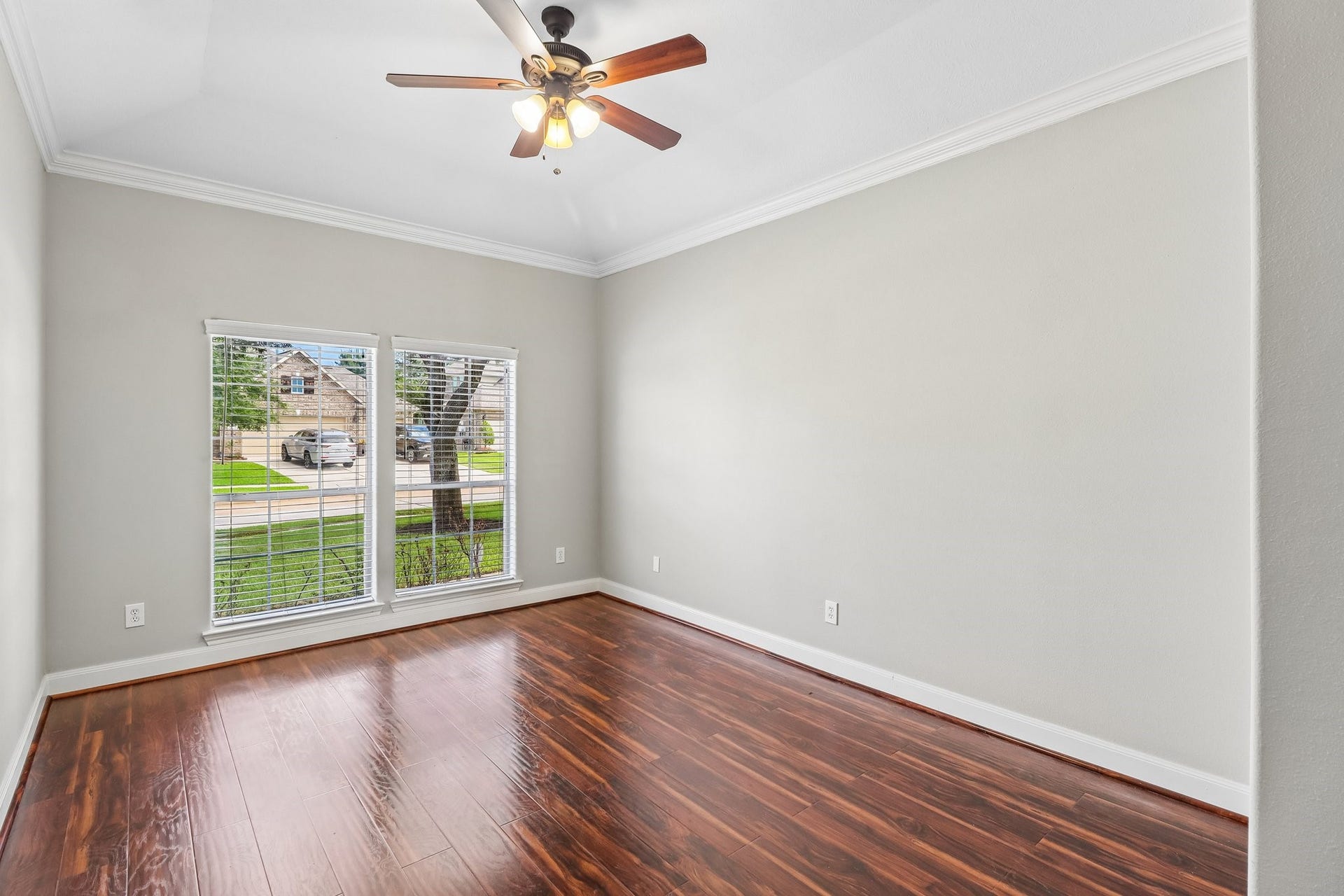 22715 Wilbur Lane, Tomball, TX 77375 Bright and airy room featuring elegant hardwood floors, large windows with natural light, and a stylish ceiling fan.