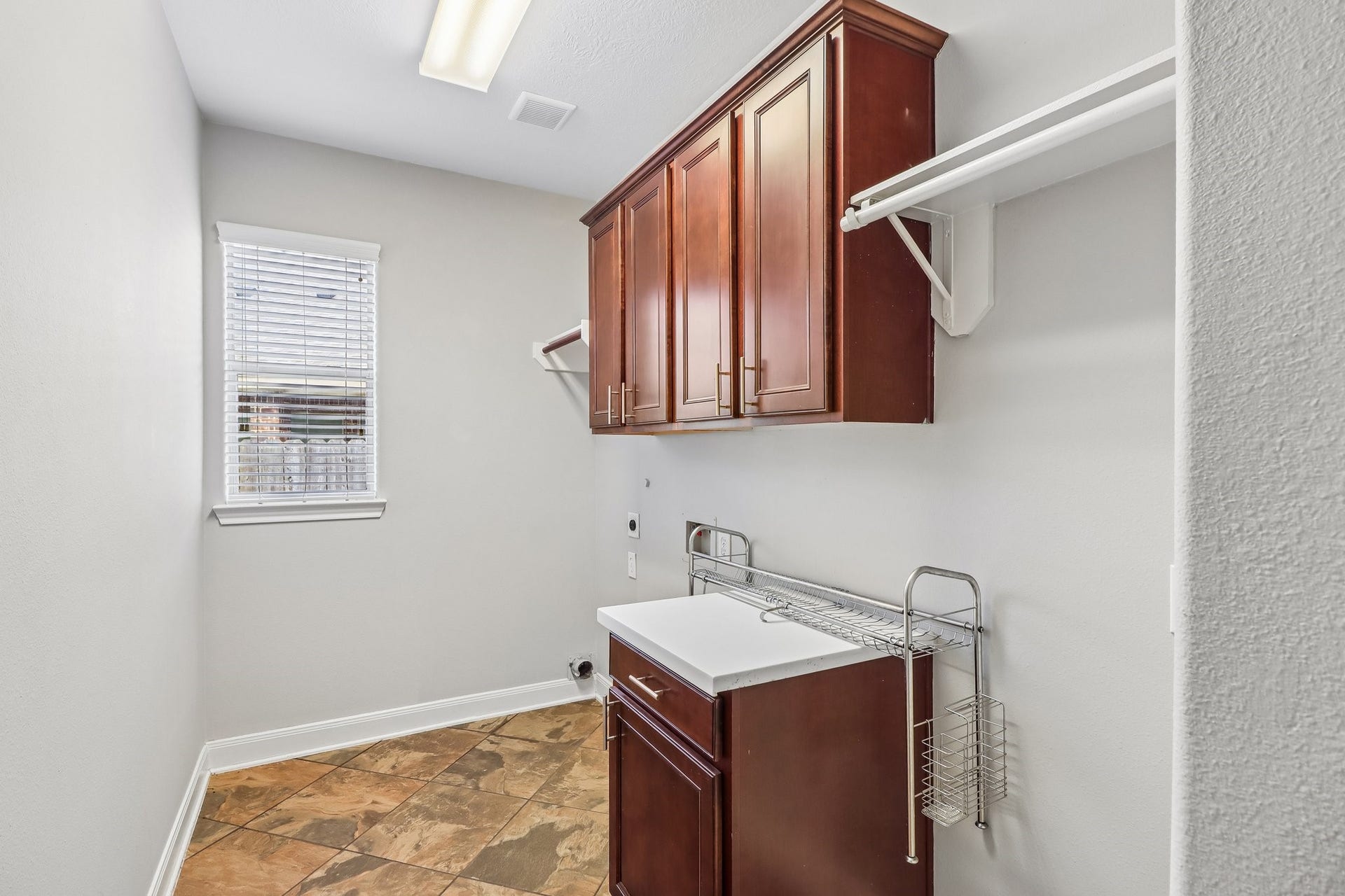 22715 Wilbur Lane, Tomball, TX 77375 Spacious laundry room with elegant wooden cabinets, a convenient countertop, and plenty of shelving, featuring natural light from a window.
