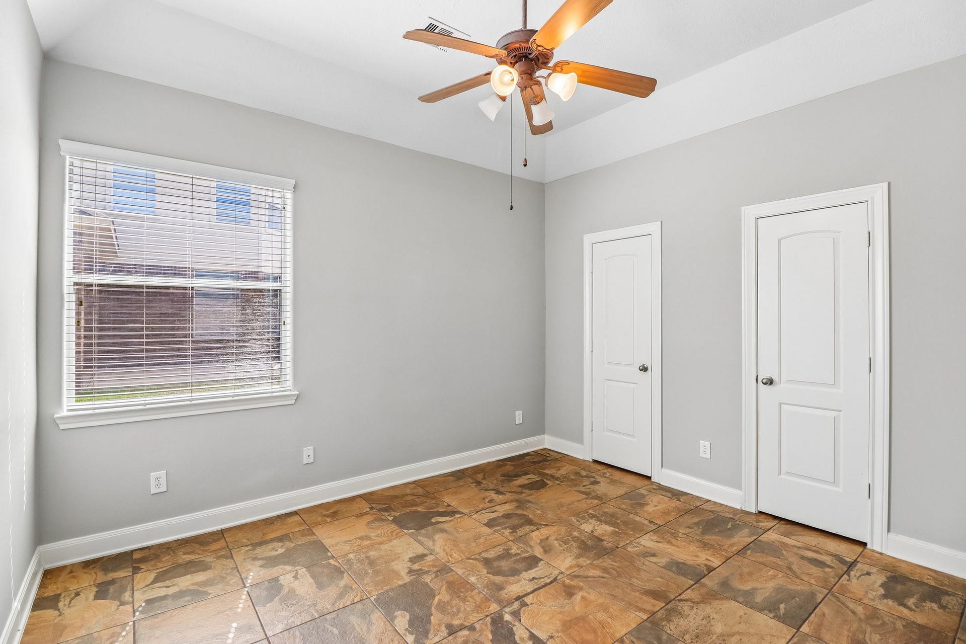 22715 Wilbur Lane, Tomball, TX 77375 Bright and inviting room with large window, elegant tiled flooring, and a stylish ceiling fan, offering ample space and two closets for storage.