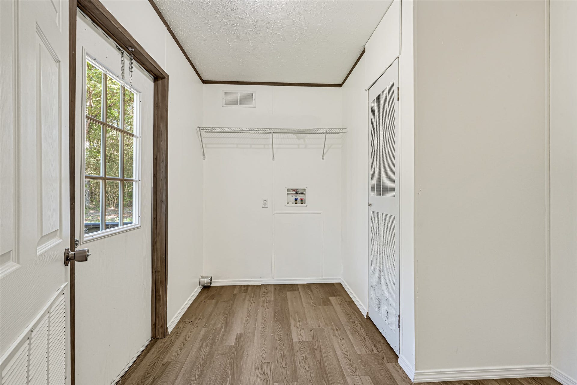 10506 Settlers Crossing, Conroe, TX 77303 Bright utility room with wood flooring, ample natural light, and convenient shelving for storage.
