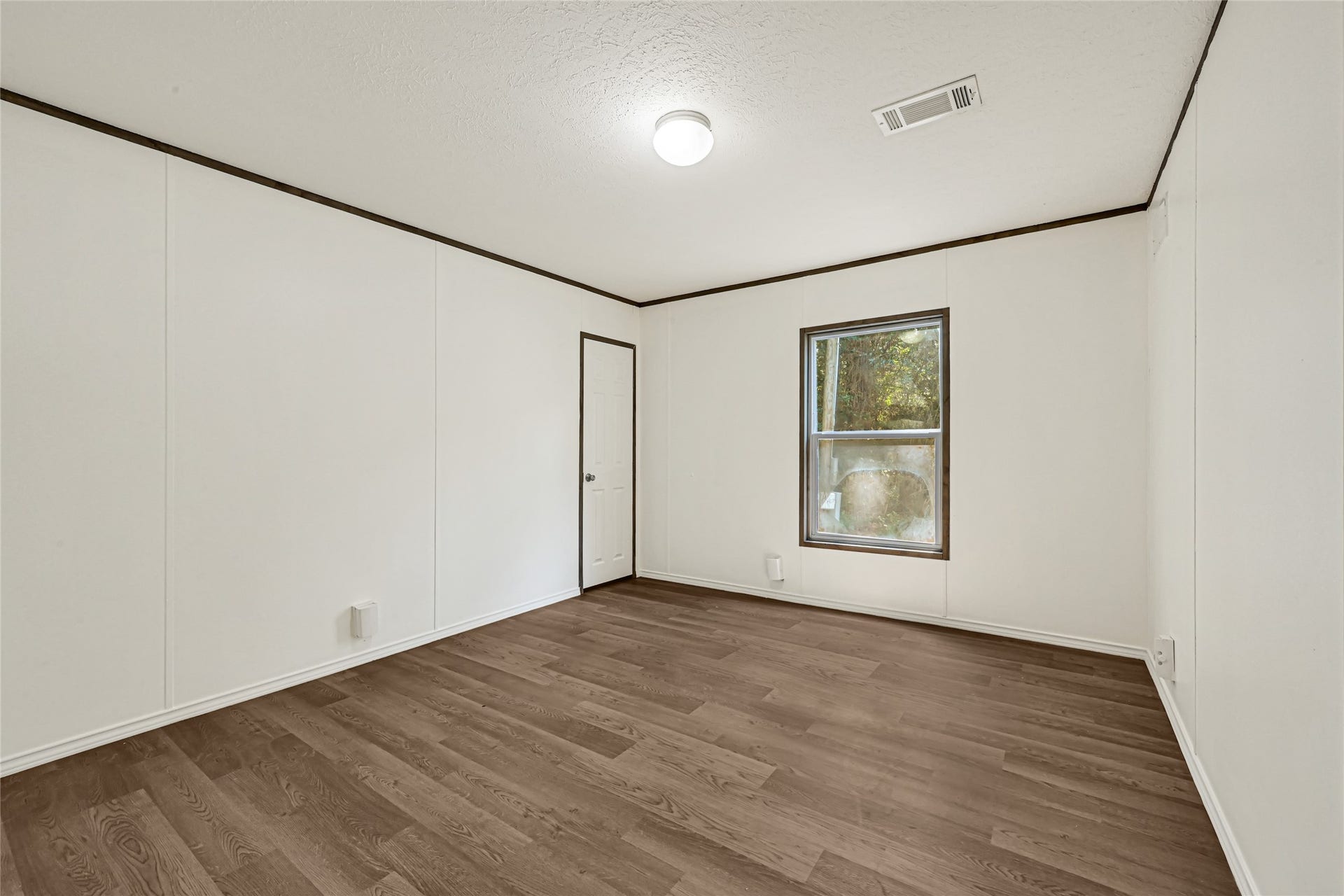 10506 Settlers Crossing, Conroe, TX 77303 Bright and airy third-bedroom with fresh white walls, sleek wood flooring, and a large window offering serene outdoor views.