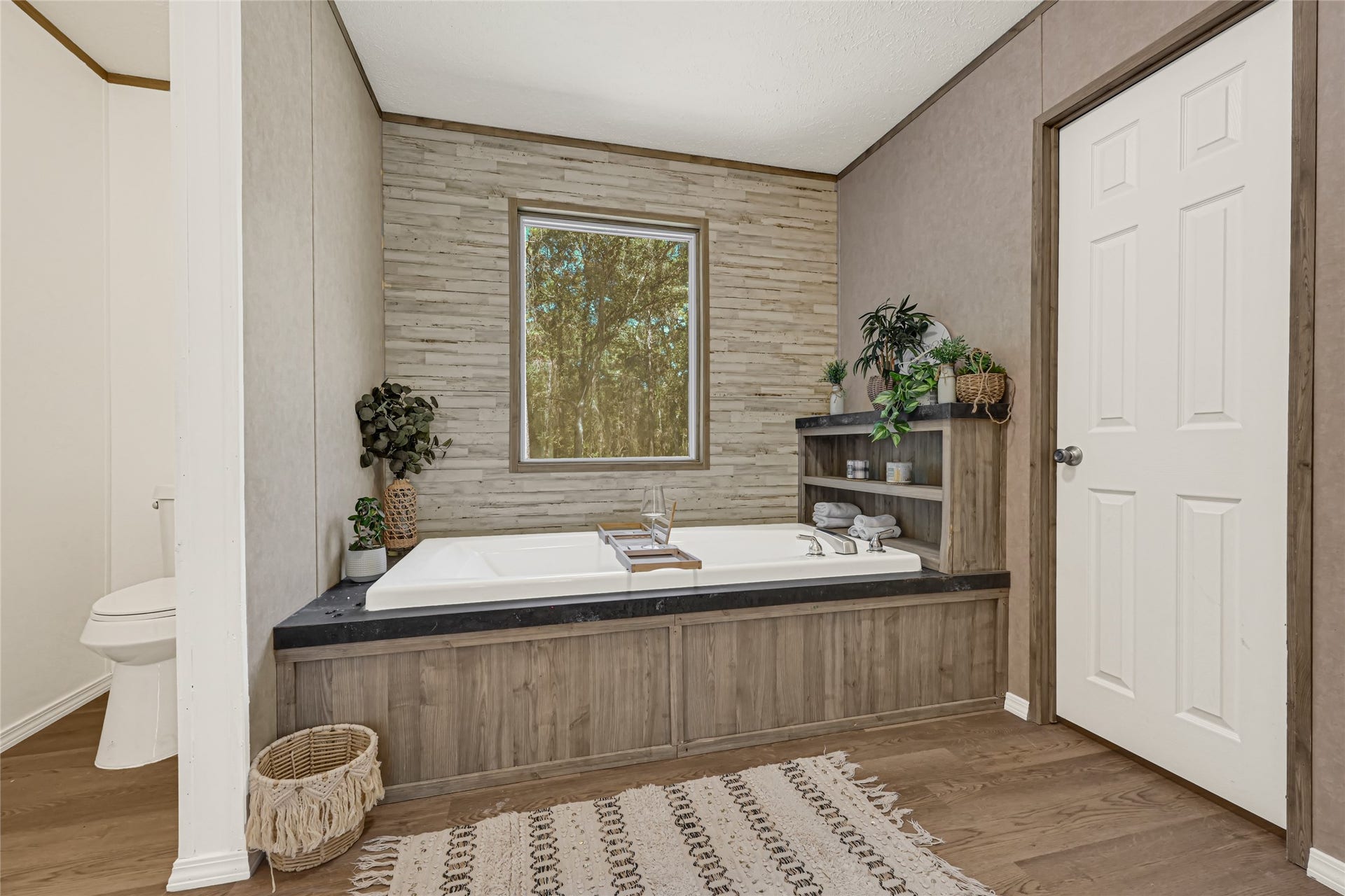 10506 Settlers Crossing, Conroe, TX 77303 Relax in this stylish bathroom featuring a luxurious soaking tub, natural wood accents, and serene views through a large window.