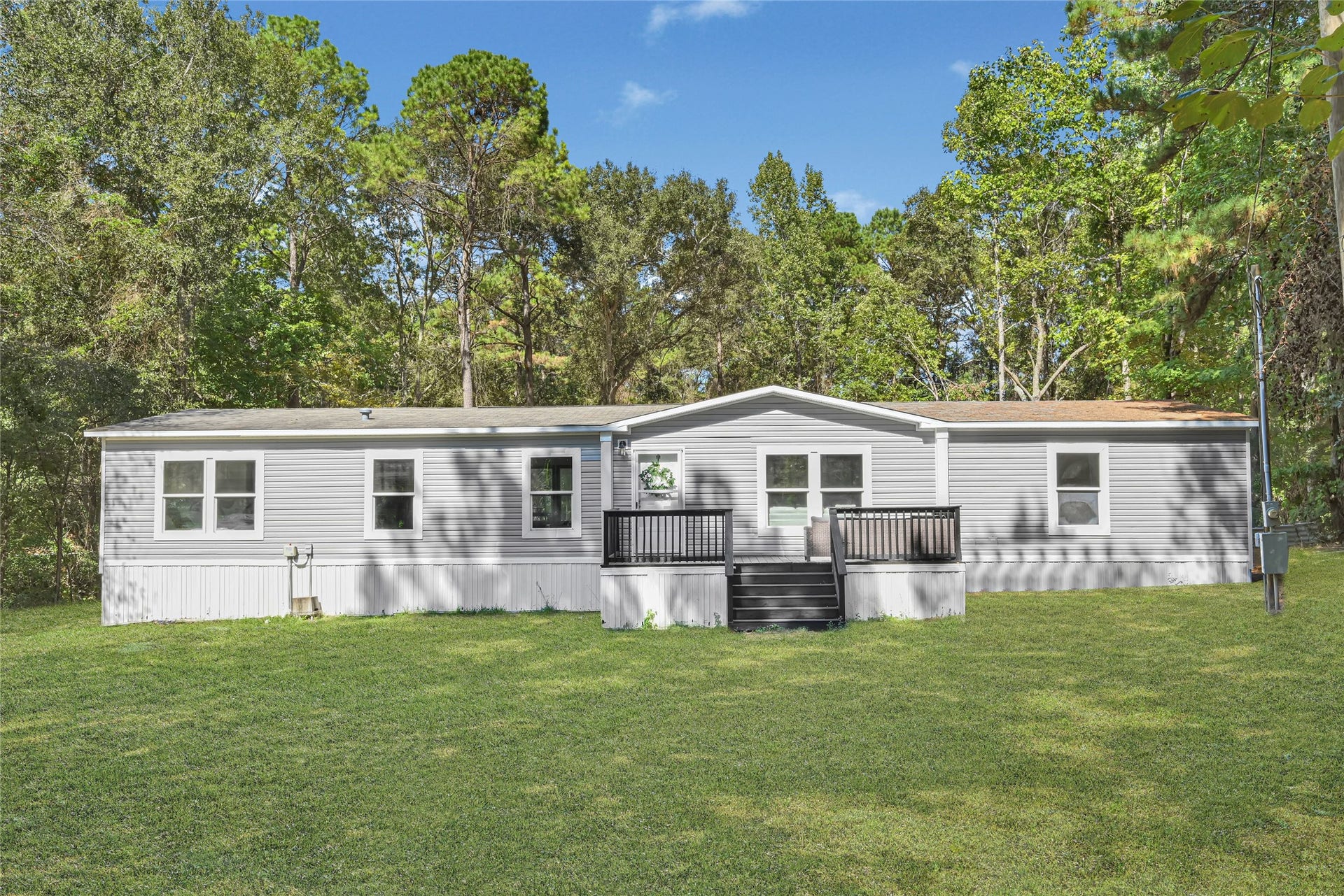 10506 Settlers Crossing, Conroe, TX 77303 Charming manufactured home nestled in 1.6 acres, featuring a well-maintained exterior with a welcoming front porch.