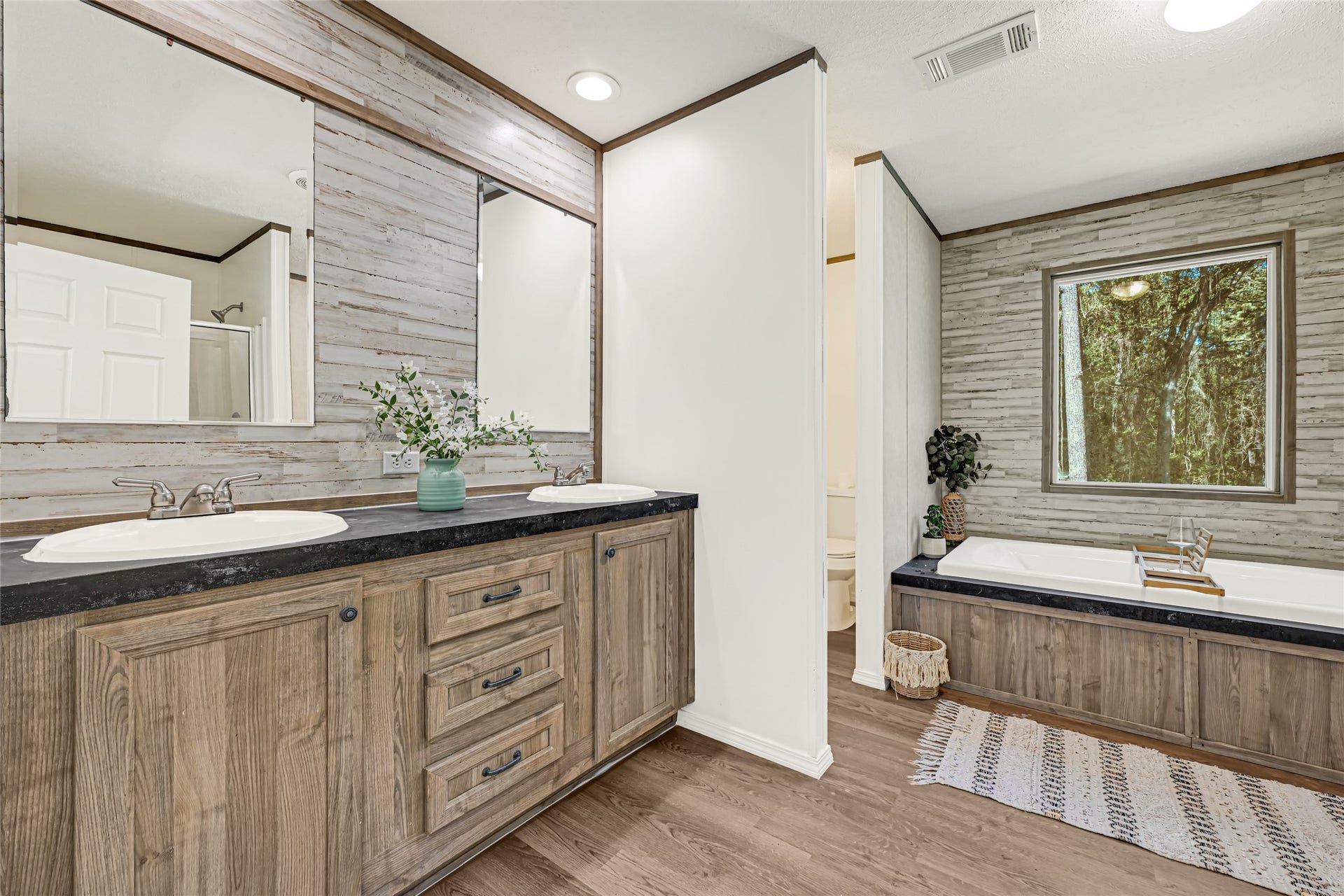 10506 Settlers Crossing, Conroe, TX 77303 Spacious bathroom featuring a dual-sink vanity with rustic wood cabinetry and a large soaking tub, complemented by stylish wood accents and a serene view.