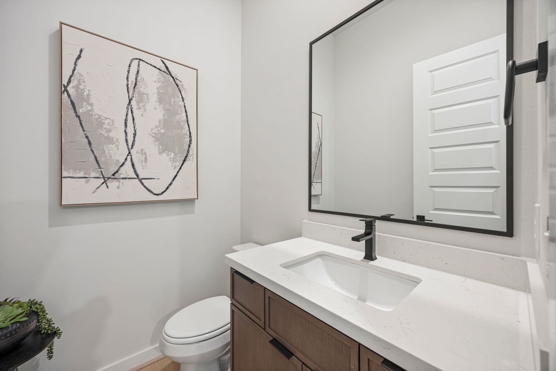 Sleek and modern half bath with stylish fixtures and artistic flair offers both convenience and elegance. **Model Home of similar layout & finishes.**