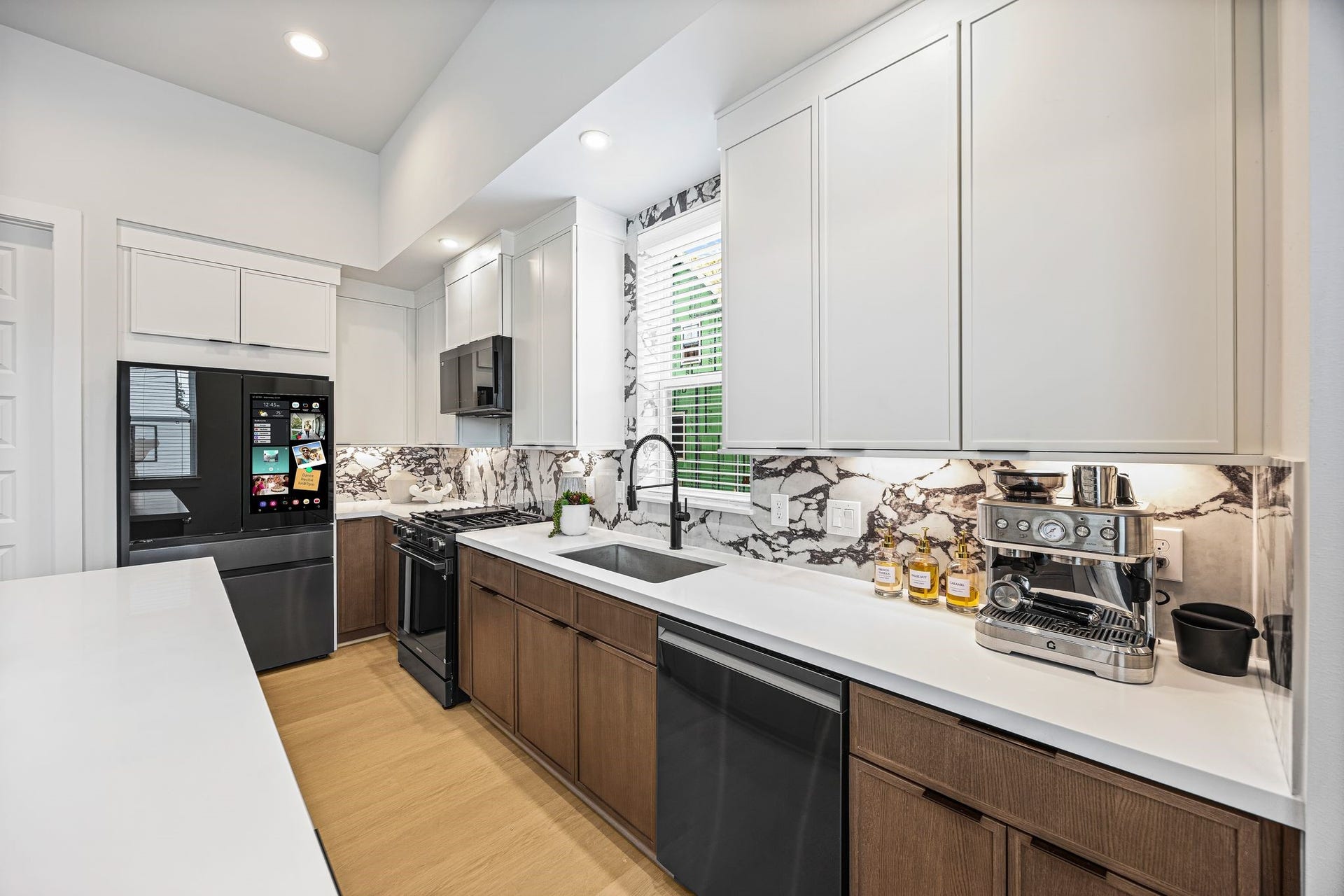 Sleek and modern kitchen featuring state-of-the-art appliances, elegant cabinetry, and a striking marble backsplash. **Model Home of similar layout & finishes.**