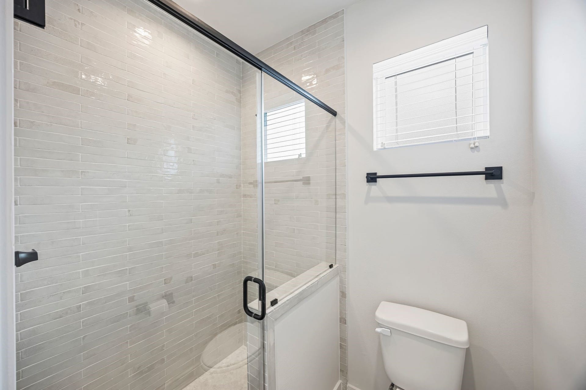 Bright and modern, the guest bathroom features sleek subway tiles and a stylish glass shower, creating a welcoming retreat for visitors. **Model Home of similar layout & finishes.**