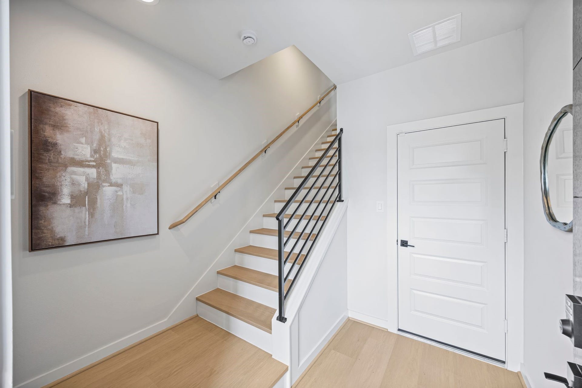Step into a stylish and welcoming entrance featuring sleek wooden stairs, modern railings, and elegant artwork, setting the tone for contemporary living. **Model Home of similar layout & finishes.**