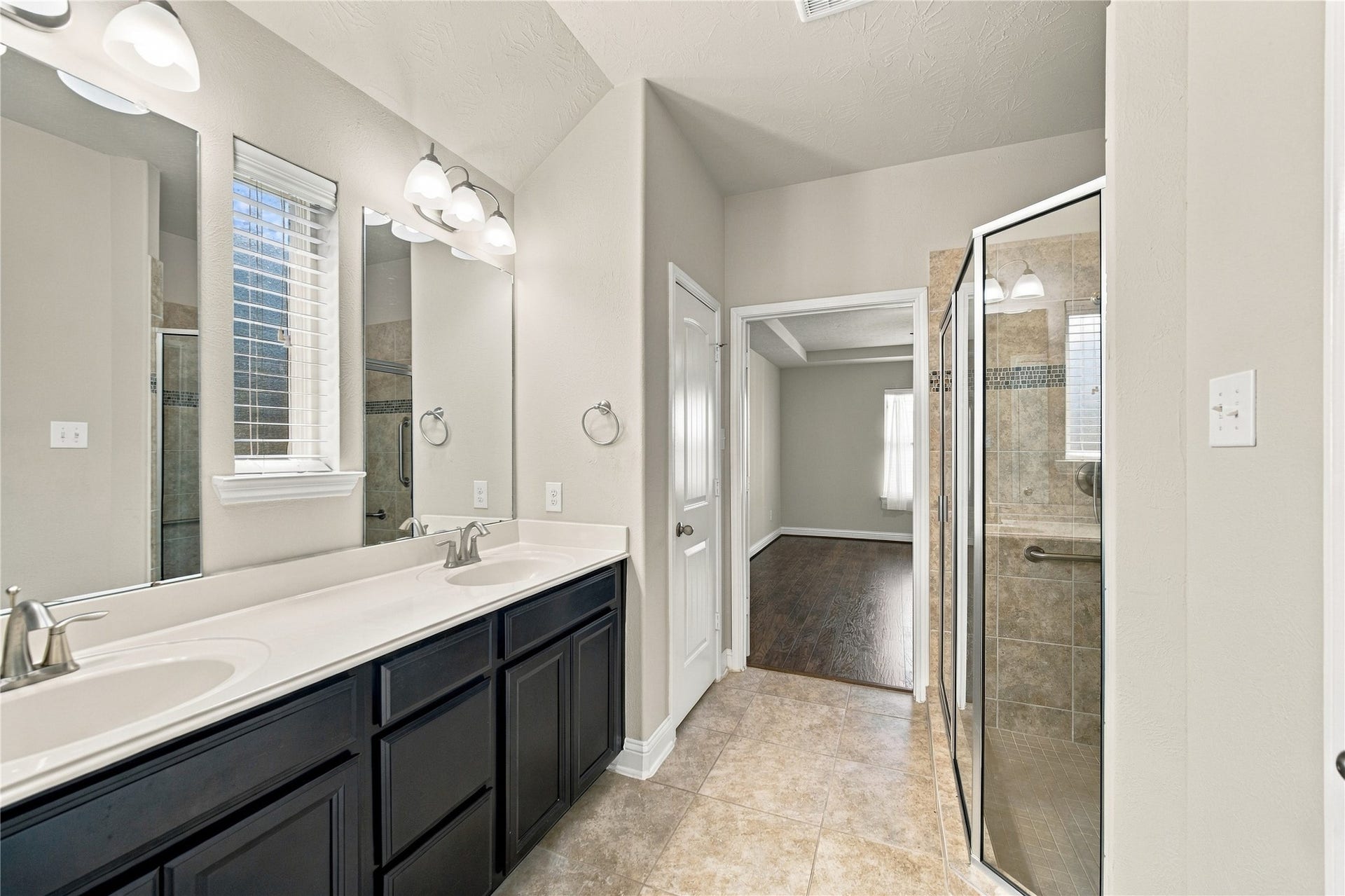 8119 W Pine Creek Bend, Cypress, TX 77433 The primary ensuite features dual sinks with cabinetry and drawers for added storage, a glass-enclosed walk-in shower, and a convenient linen closet.