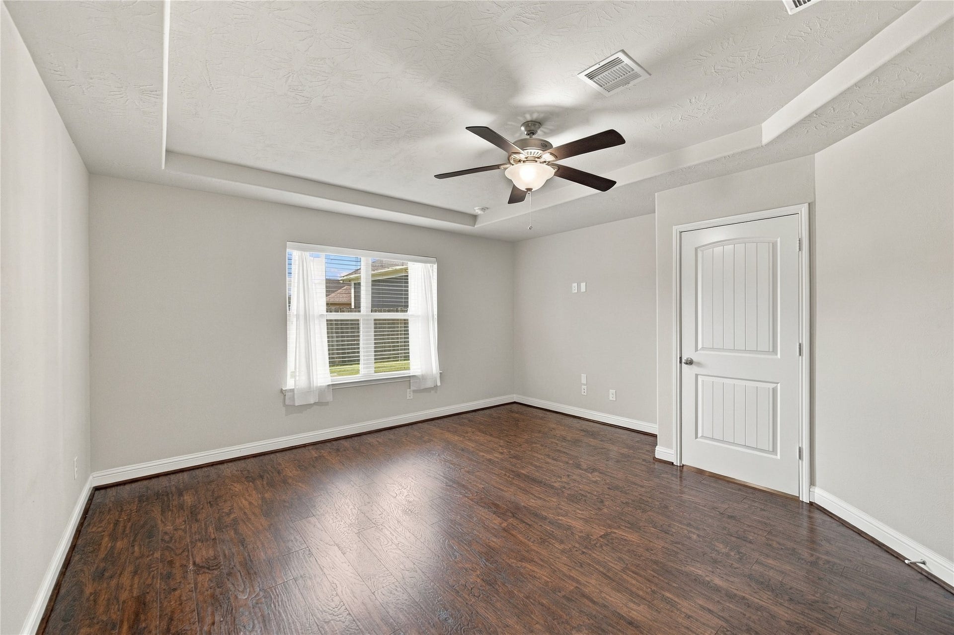8119 W Pine Creek Bend, Cypress, TX 77433 The beautiful wood flooring continues into the primary bedroom, where tray ceilings add architectural detail to the room.