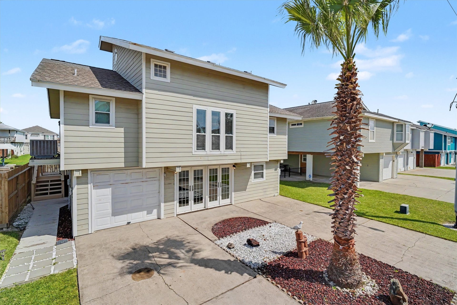 Street side view of home. The french doors enter into the downstairs flex room. The palm trees were recently trimmed