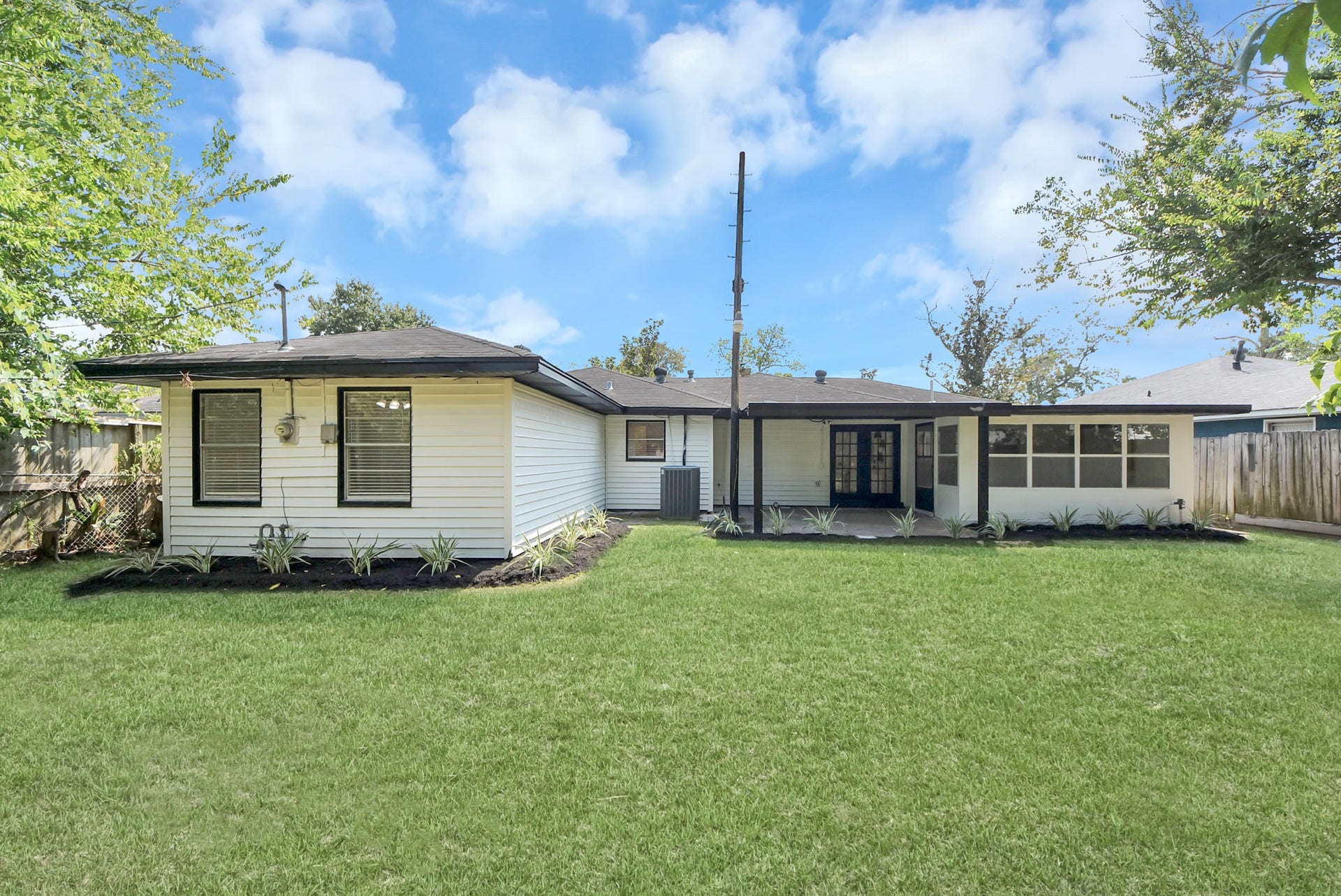 9610 Westview Drive, Houston, TX 77055 Beautifully maintained rear yard showcasing a generous lawn, mature landscaping, and a covered patio area along the back of the home. Clean garden beds and thoughtfully arranged greenery enhance the outdoor setting while creating a comfortable, private backdrop.
