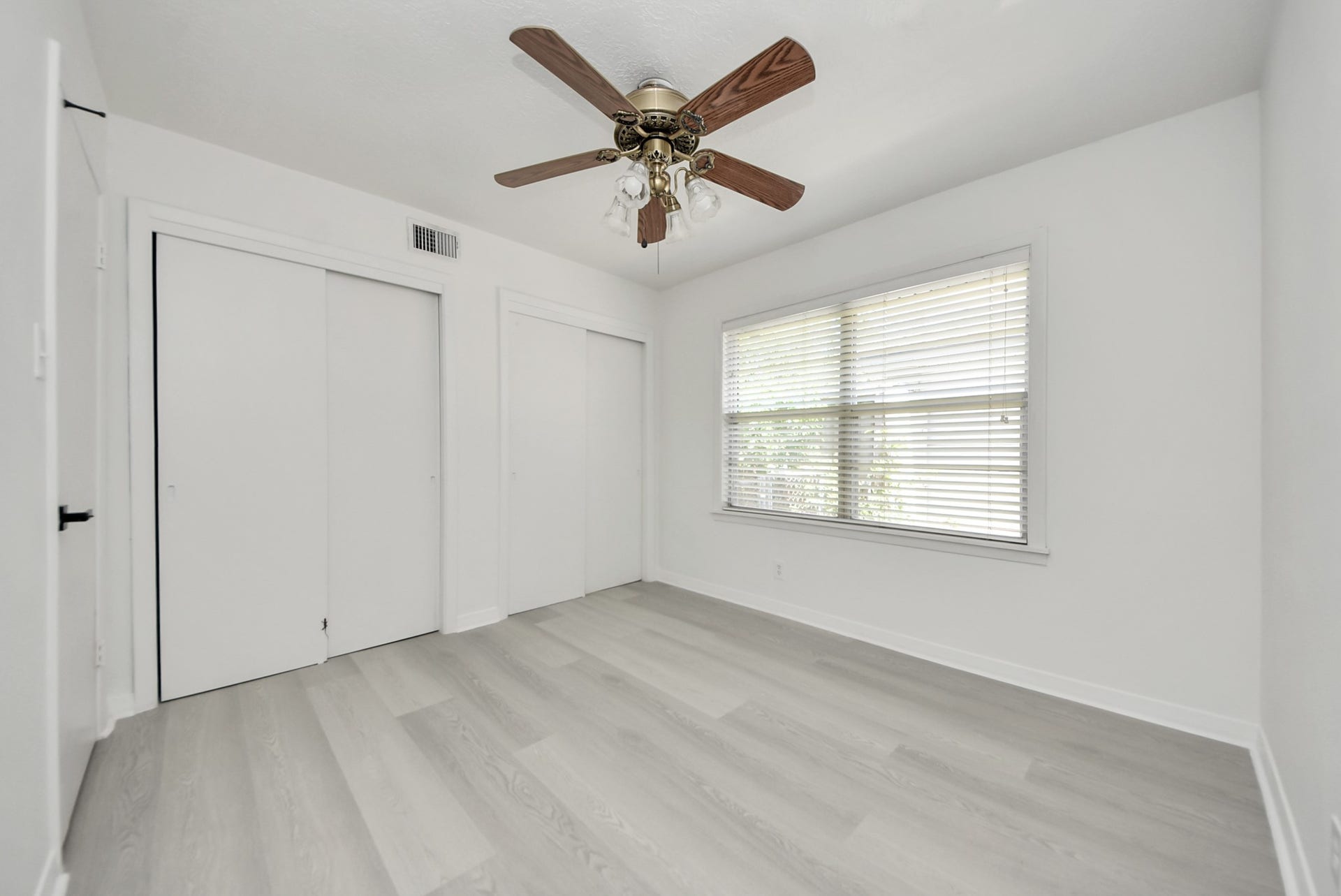 9610 Westview Drive, Houston, TX 77055 Bright and airy room featuring sleek light wood flooring, a ceiling fan, and ample natural light from a large window with blinds, complemented by convenient closet space.