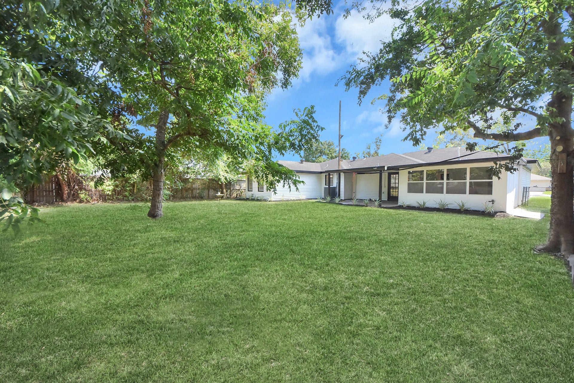9610 Westview Drive, Houston, TX 77055 Expansive backyard retreat featuring a broad, well-maintained lawn framed by mature trees and lush greenery. The rear exterior offers a peaceful setting with ample outdoor space, established landscaping, and a welcoming connection to the home.