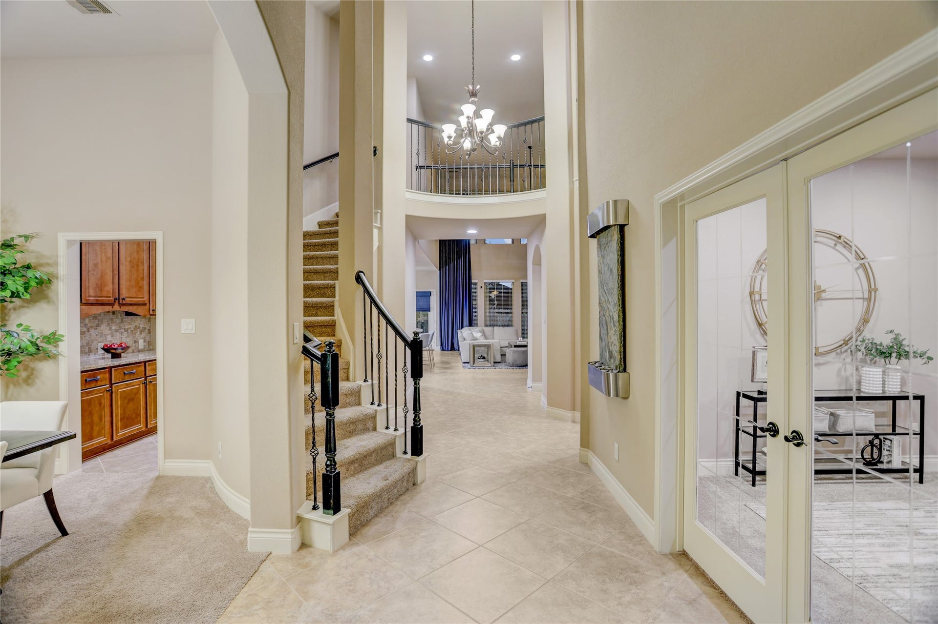 13308 Paxton Hill Court, Pearland, TX 77584 Step into a grand two-story foyer featuring soaring ceilings, elegant tile flooring, a sweeping staircase with wrought-iron balusters, and a stunning overlook from the second floor. French doors open to a private home office, while the formal dining room offers the perfect space for entertaining. The entry sets the tone for the home's spacious design.