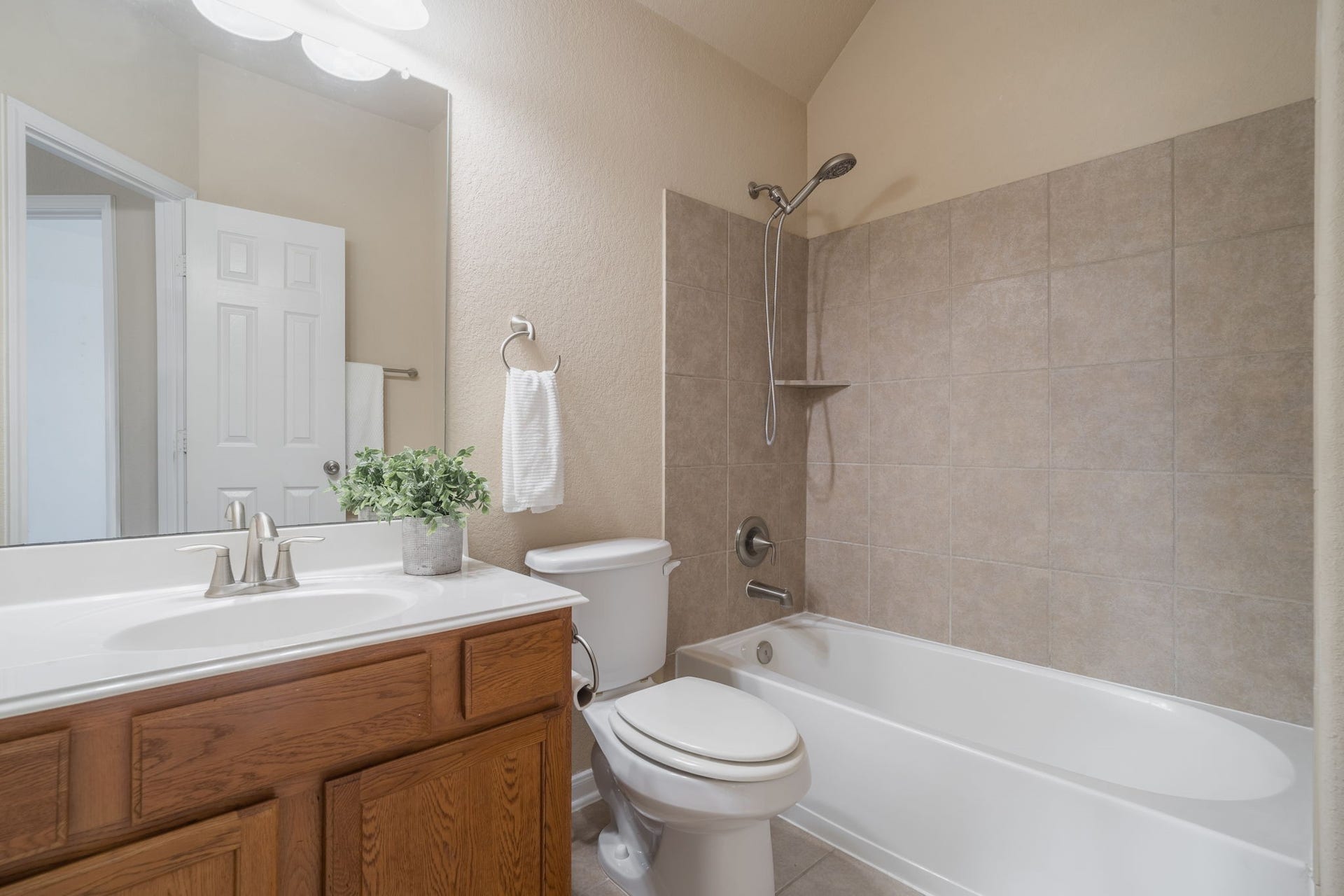 7222 Stevenson Drive, Missouri City, TX 77459 Upstairs secondary bath featuring a spacious vanity with wood cabinetry, a tub/shower combination with tile surround & a convenient handheld showerhead.