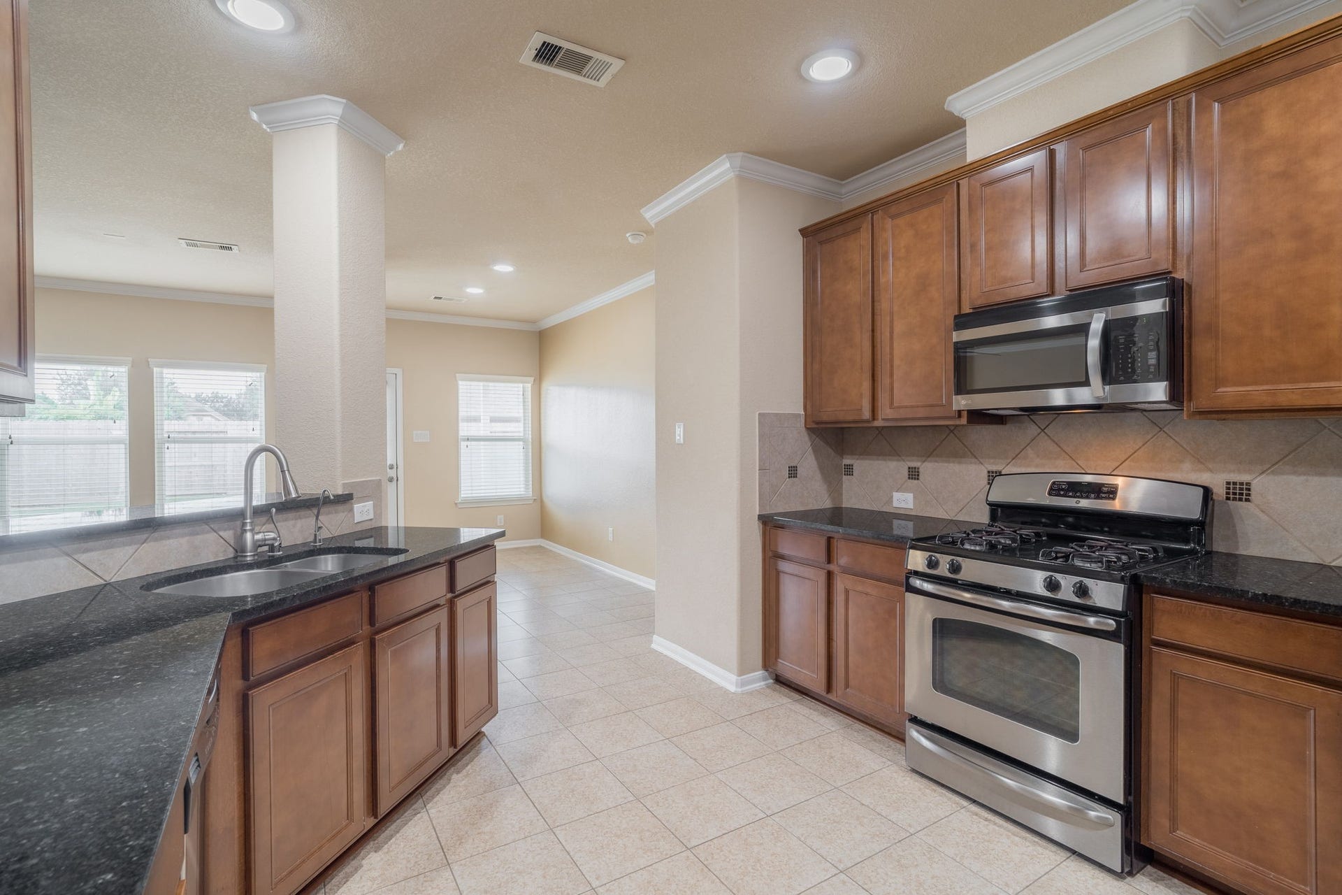 7222 Stevenson Drive, Missouri City, TX 77459 Spacious kitchen featuring rich wood cabinetry, granite countertops, tile backsplash & stainless steel appliances, including a gas range.