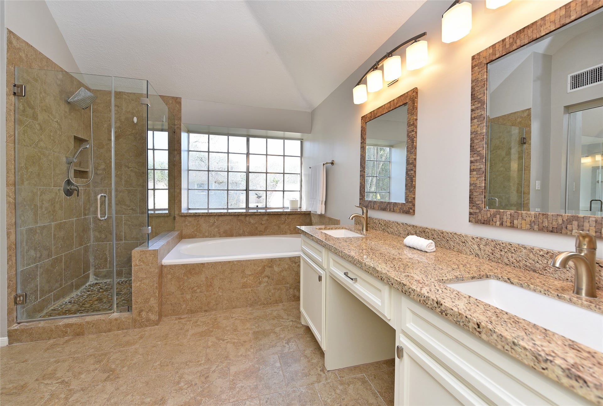 907 Sugarfield Court, Sugar Land, TX 77498 The remodeled primary bath features nice sized shower with pebble stone floor, a large garden tub and double sinks.