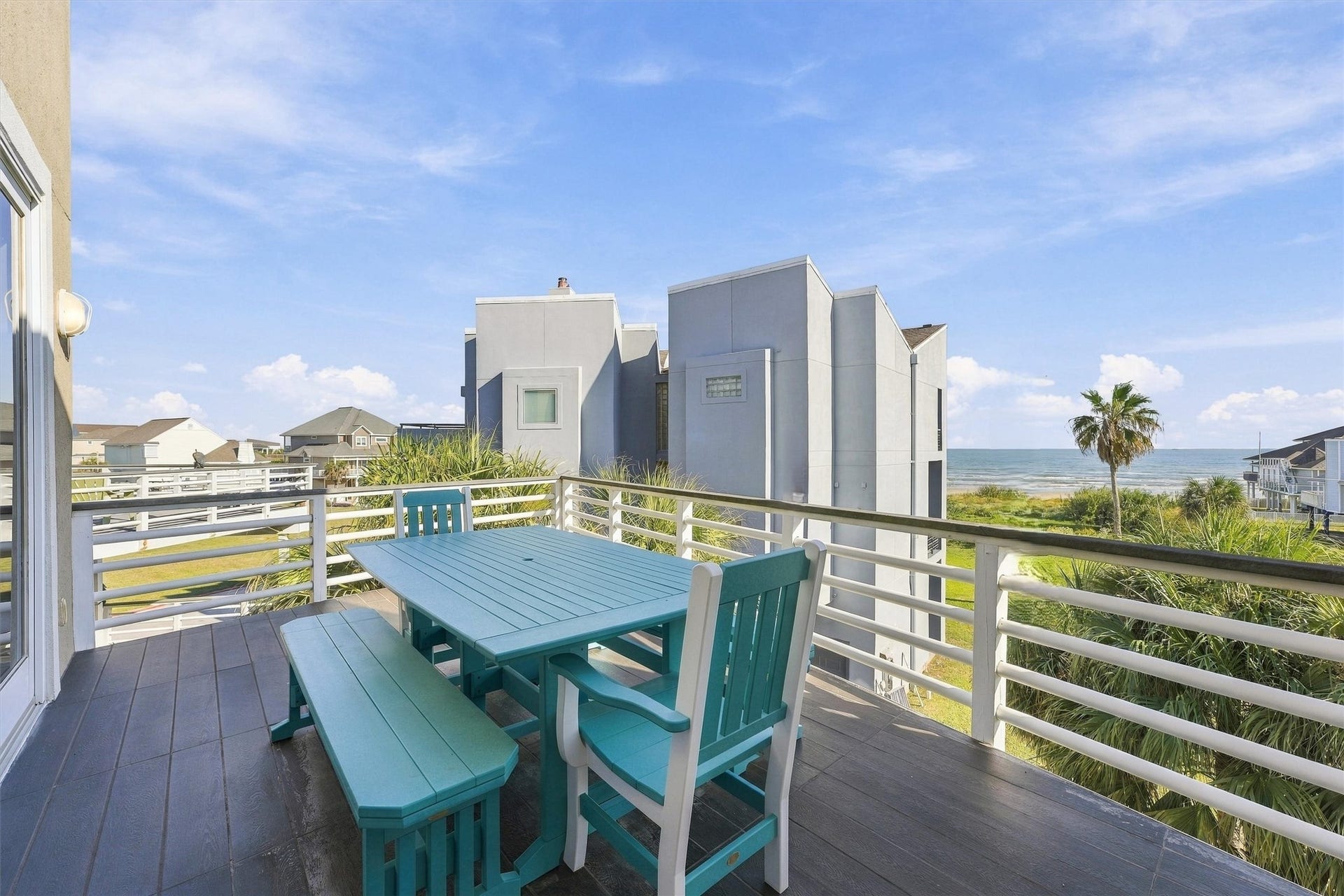 4207 Barataria Court, Galveston, TX 77554 Start the morning with coffee and beach views, then gather for dinner in the coastal breeze. This spacious balcony offers an inviting setting for outdoor meals with palms and rolling waves beyond.