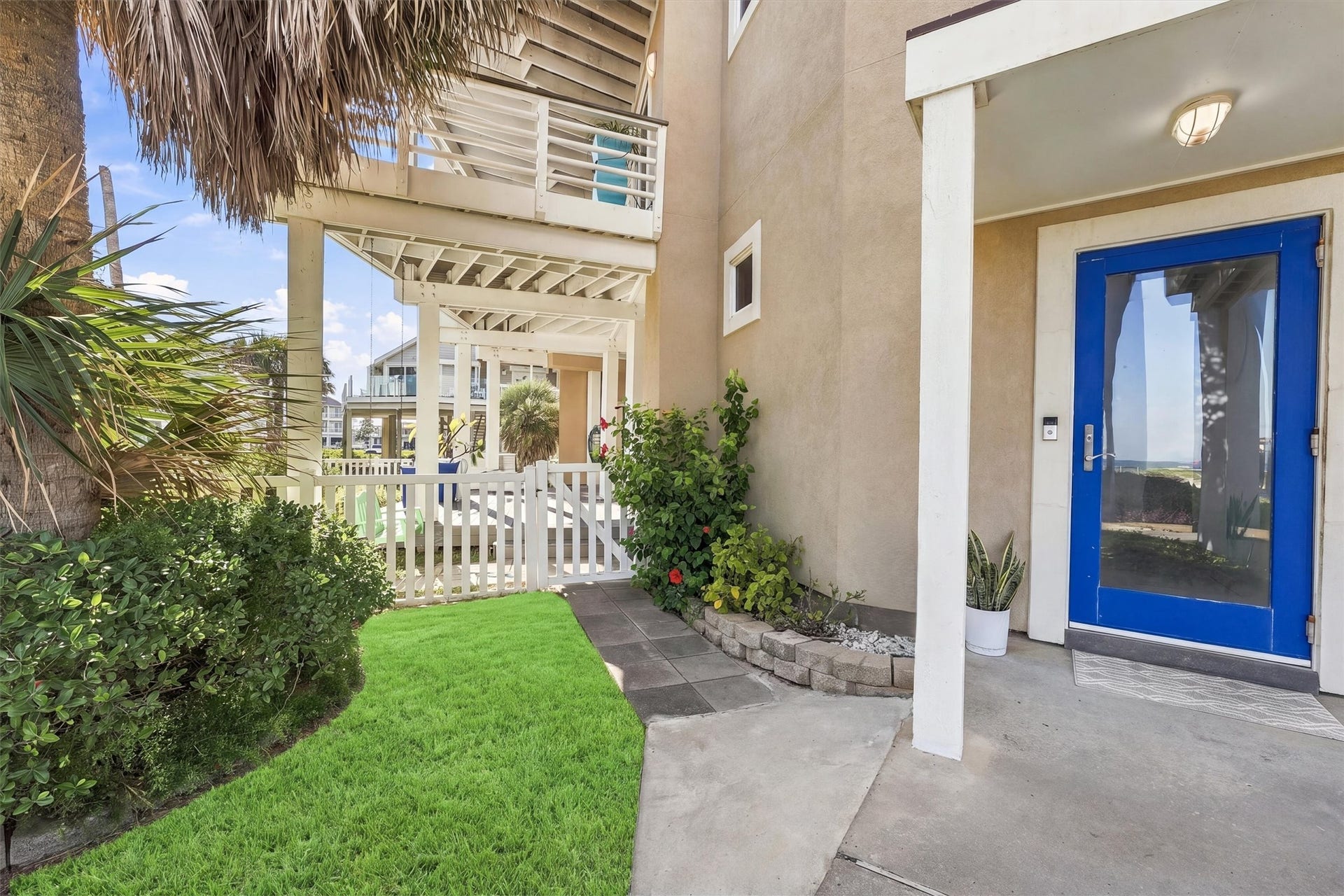 4207 Barataria Court, Galveston, TX 77554 A vibrant blue door, tropical greenery, and a white picket gate welcome you home. This inviting entrance sets the tone for the relaxed island living.