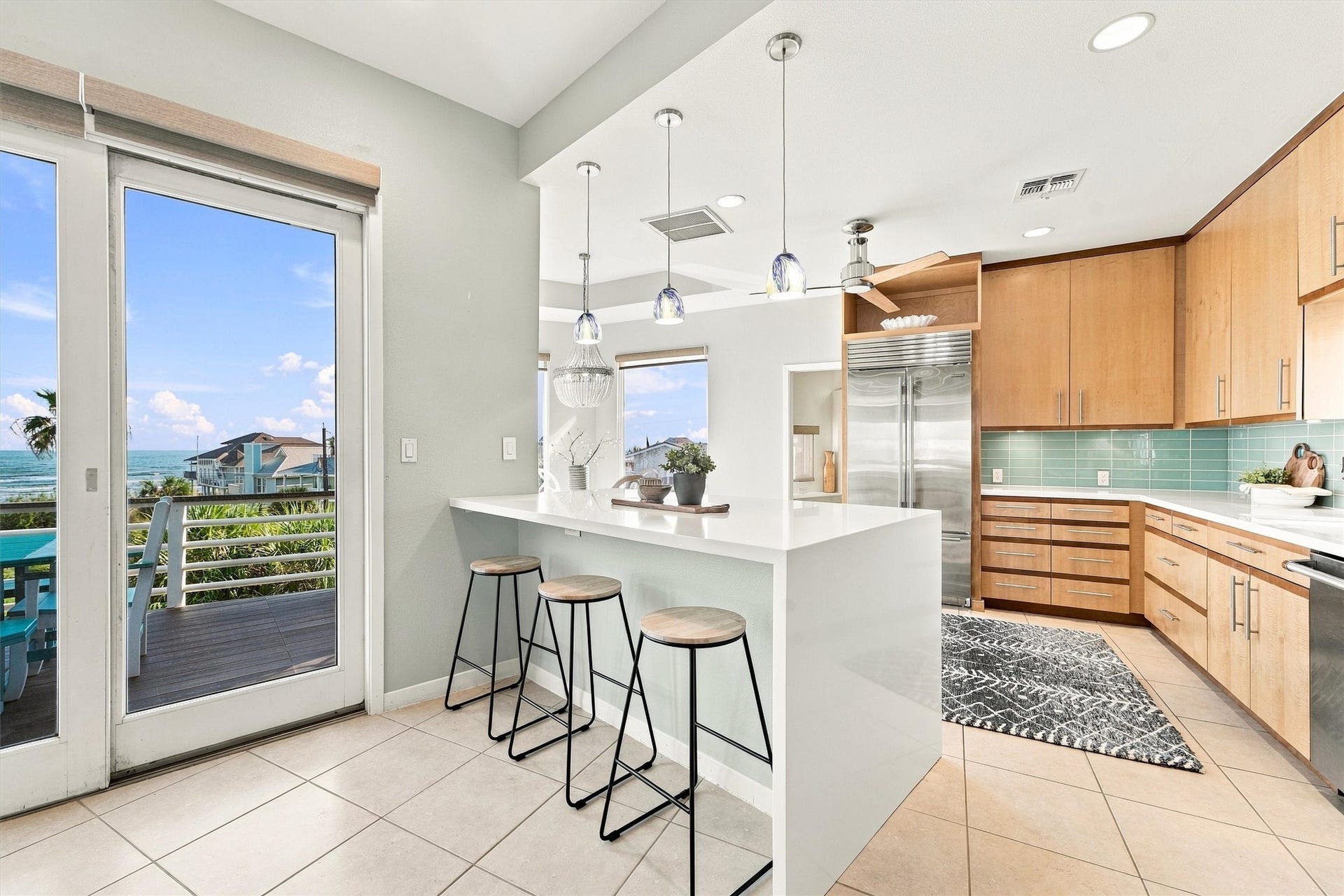 4207 Barataria Court, Galveston, TX 77554 Prepare breakfast with the water in view, share stories across the breakfast bar, then take your coffee onto the balcony. Warm wood cabinetry, crisp white counters, and a sea-glass-colored backsplash create a welcoming coastal kitchen.